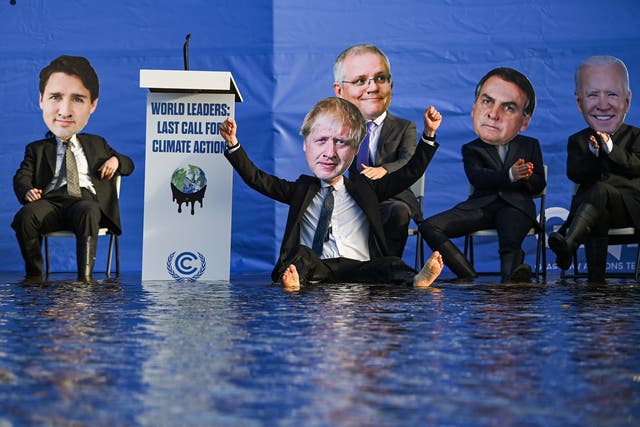 <p>Activistas disfrazados de líderes mundiales se sientan en una balsa en el canal de Forth y Clyde, en protesta por la falta de acción de los gobiernos para reducir las emisiones</p>