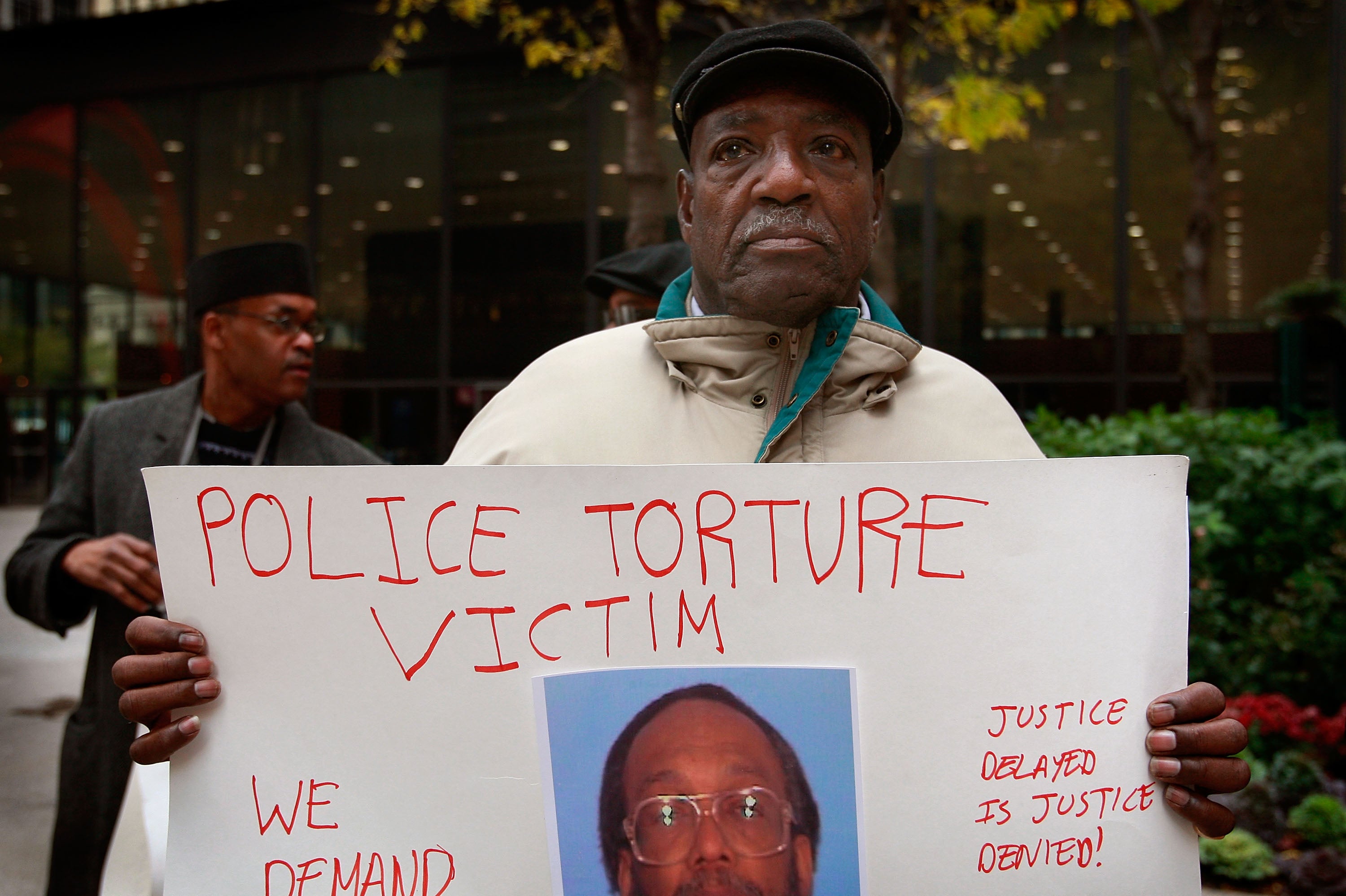 Aaron Cheney demonstrates outside the federal courthouse where former Chicago Police Commander Jon Burge was attending a hearing on charges he obstructed justice and committed perjury for lying while under oath during a 2003 civil trial about decades-old Chicago police torture allegations October 27, 2008 in Chicago, Illinois.