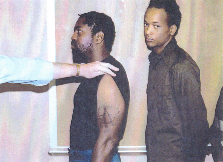 An officer rolls up Nathson Fields’s sleeve to reveal a gang tattoo during a police lineup.