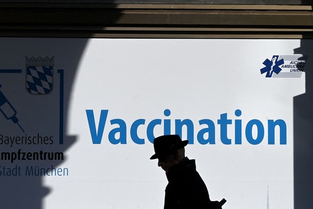 <p>A man walks past a vaccination centre in Munich</p>