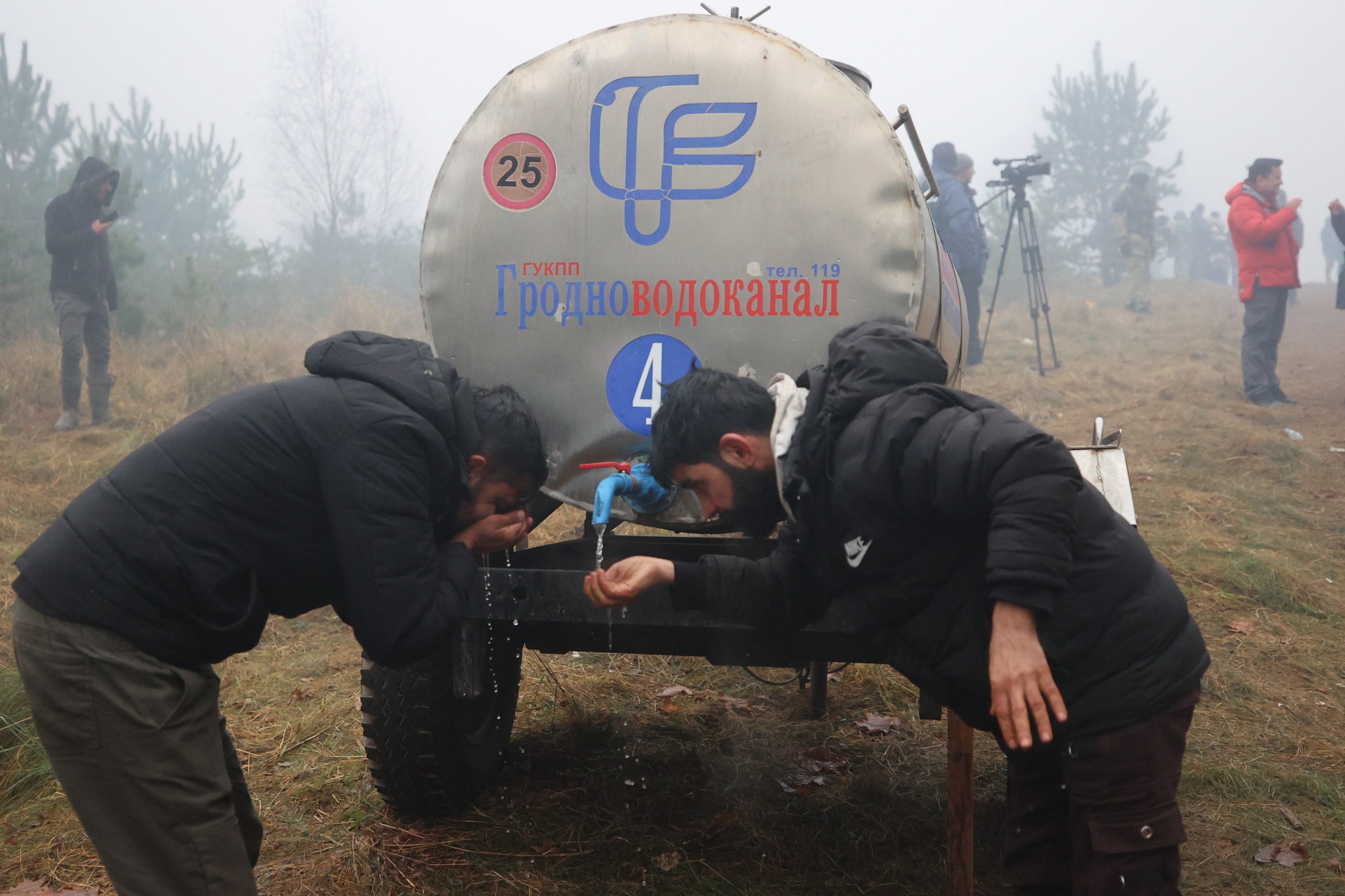 Migrants receive water at their camp at the Belarus-Polish border