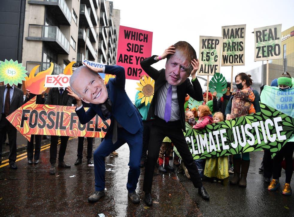 <p>Climate activists wear masks of president Joe Biden and Boris Johnson at an anti-fossil fuel protest in Glasgow during Cop26</p>