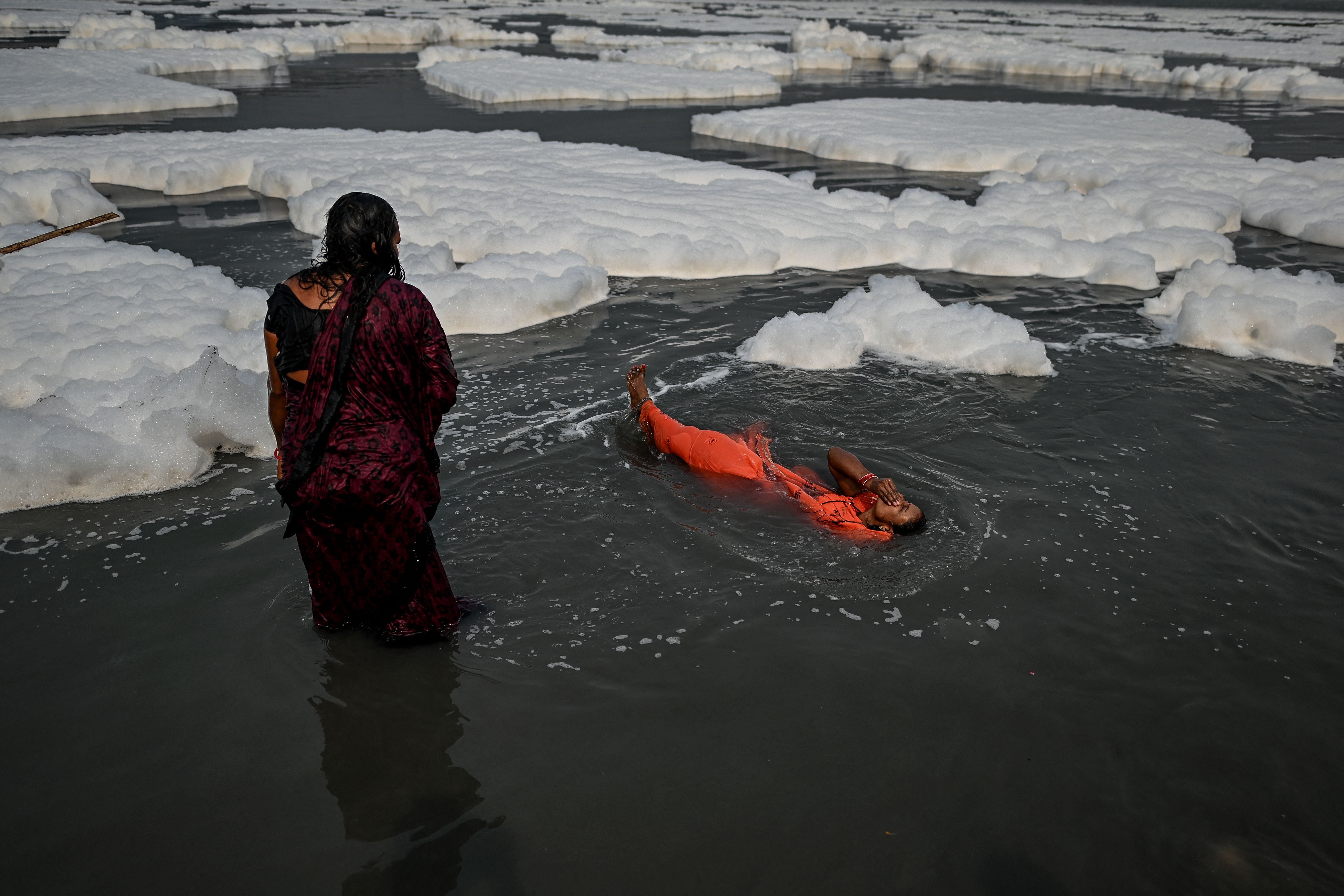Women bathe among the foam in the Yamuna