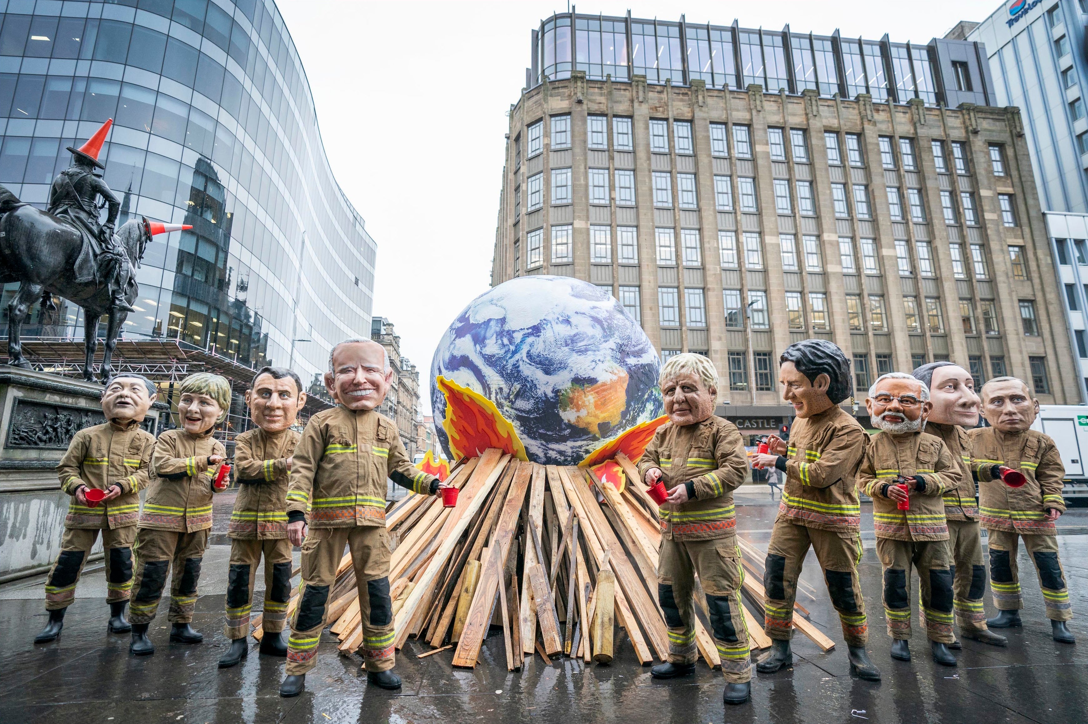 Campaigners wearing 'big heads' of world leaders, including Boris Johnson, Joe Biden, Justin Trudeau and Narendra Modi gather for Oxfam's 'Ineffective Fire-Fighting World Leaders' protest performance in front of a 10 foot globe with a simulated bonfire, during the official final day of the Cop26 summit in Glasgow