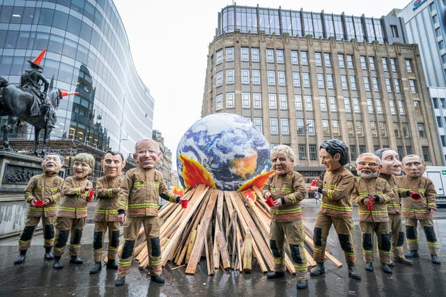 <p>Campaigners wearing 'big heads' of world leaders, including Boris Johnson, Joe Biden, Justin Trudeau and Narendra Modi gather for Oxfam's 'Ineffective Fire-Fighting World Leaders' protest performance in front of a 10 foot globe with a simulated bonfire, during the official final day of the Cop26 summit in Glasgow</p>