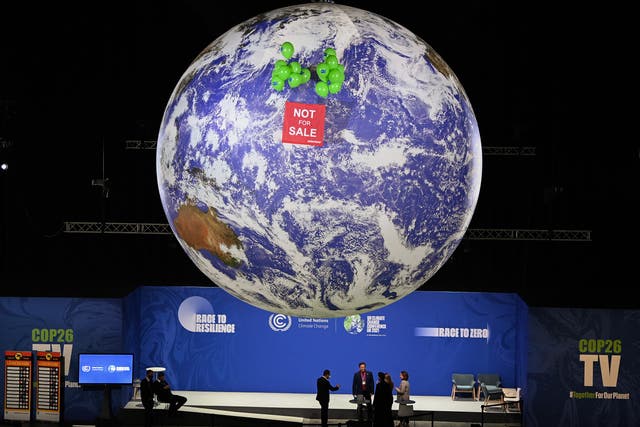 <p>Greenpeace float a ‘not for sale’ sign above a globe in the blue zone of Cop26 </p>