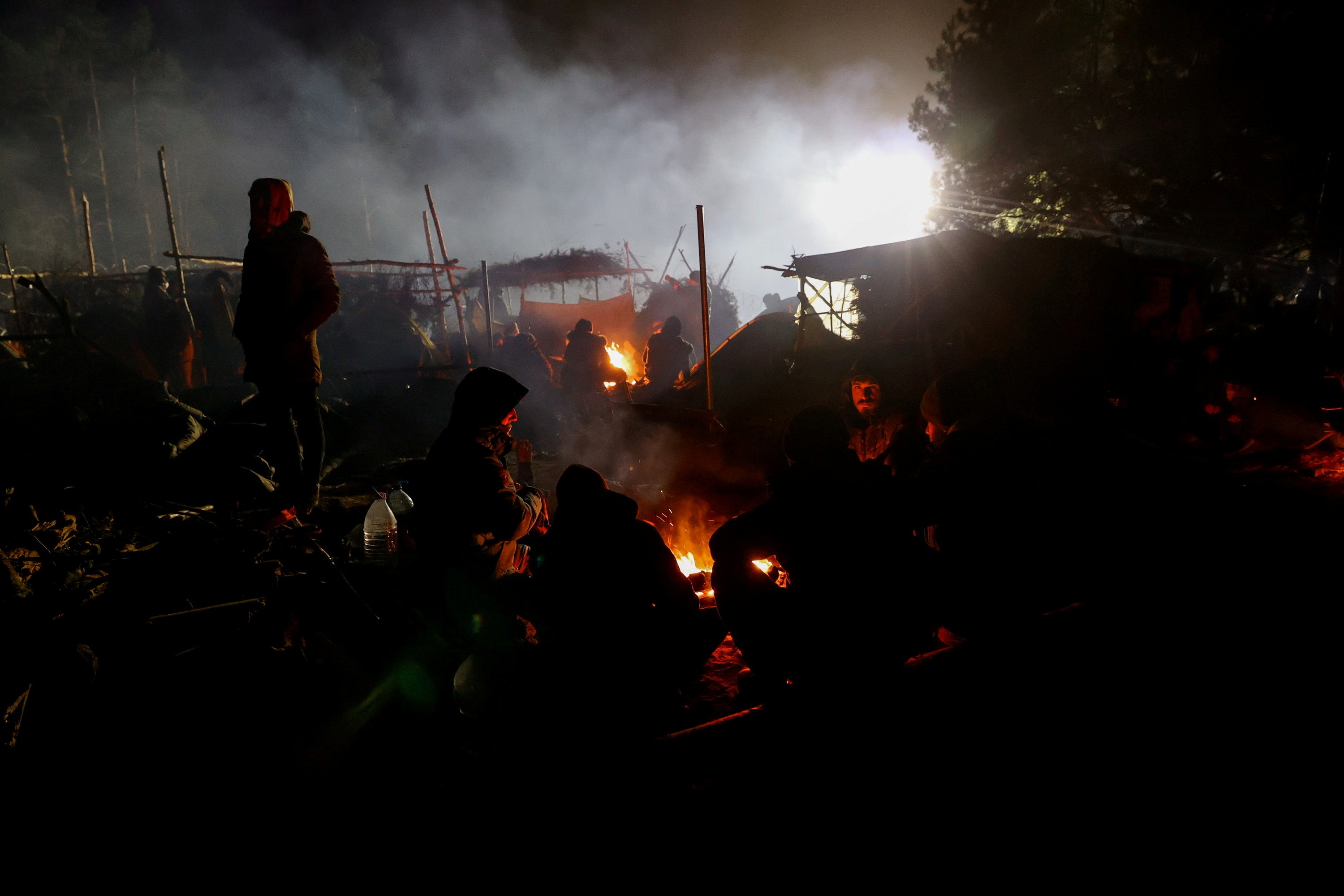 Migrants gather around a fire in a makeshift camp