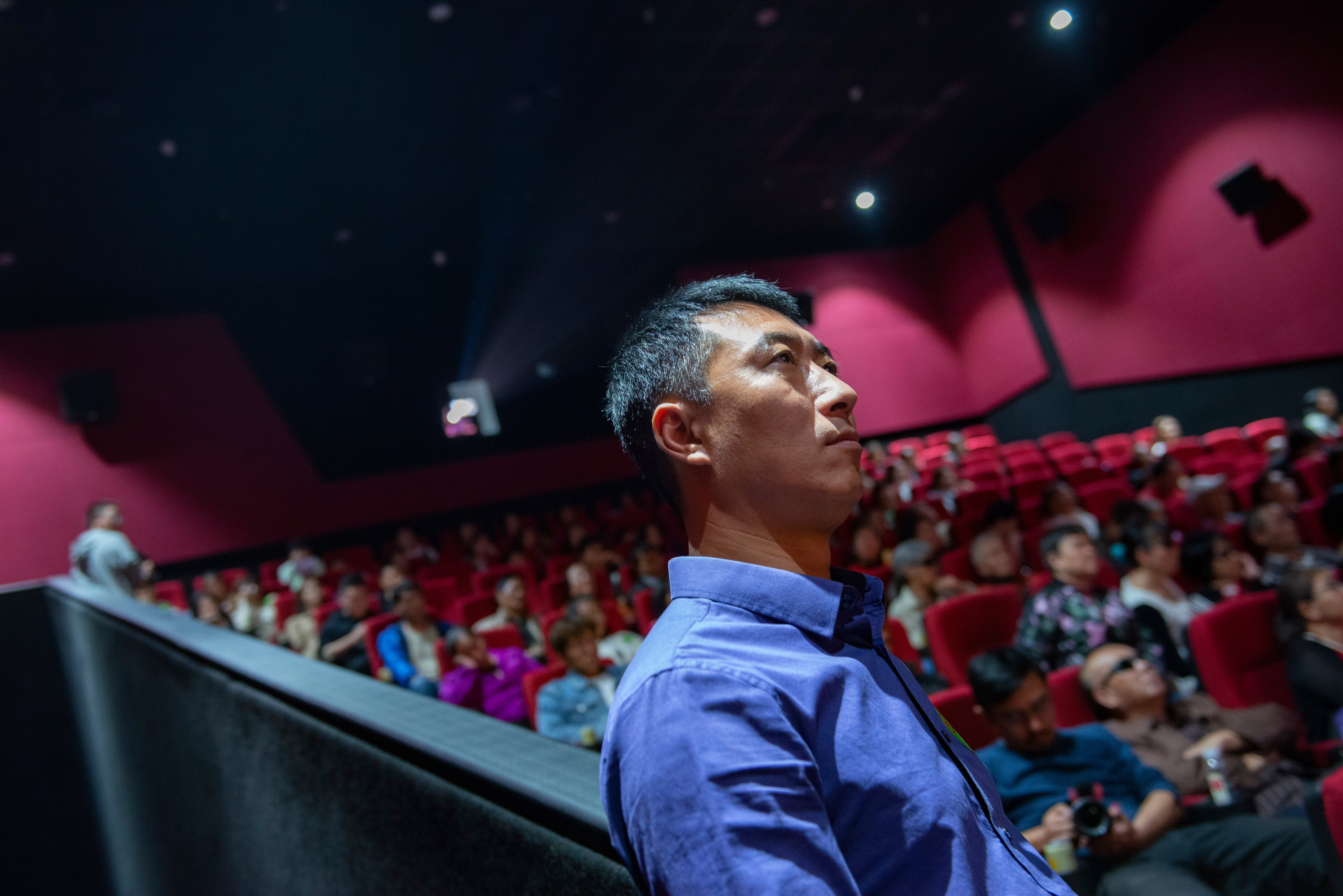 Zhou Quan, the founder of Xin Deng Theatre, narrates a movie for a blind and visually impaired audience at a cinema in Kunming in 2019