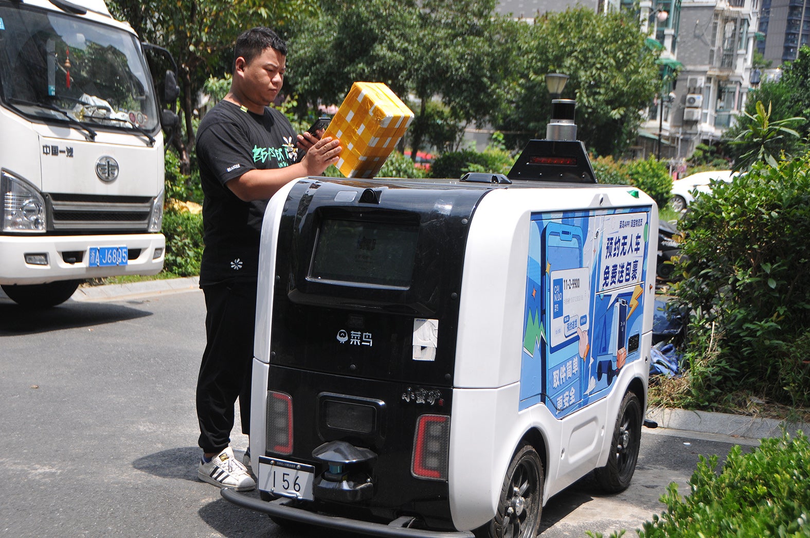 A man picks up a parcel from a Cainiao autonomous delivery vehicle at a community in Hangzhou, Zhejiang province, in August