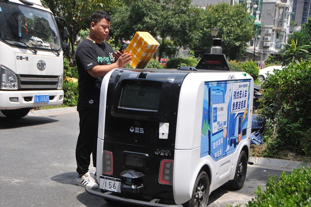 <p>A man picks up a parcel from a Cainiao autonomous delivery vehicle at a community in Hangzhou, Zhejiang province, in August</p>