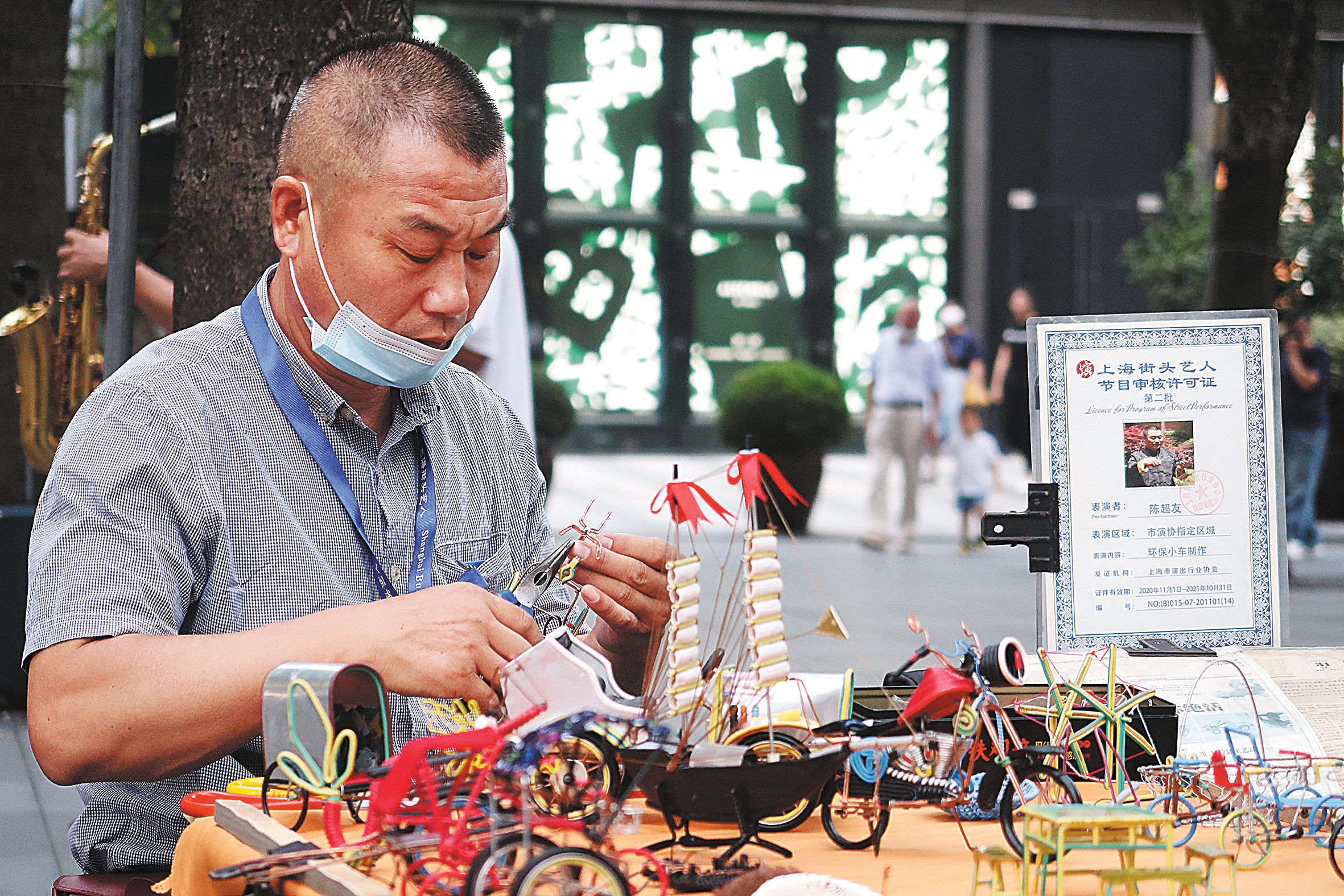 A handicraft artist makes models in the square in front of Jing’an Park in Shanghai