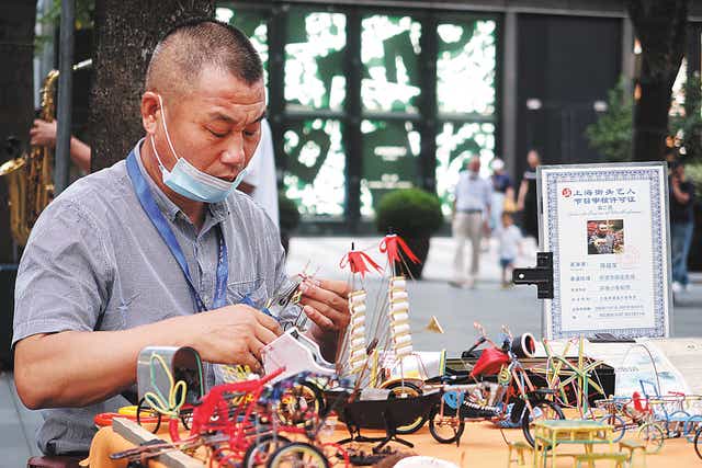 <p>A handicraft artist makes models in the square in front of Jing’an Park in Shanghai</p>