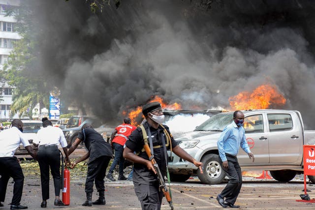 <p>People extinguish fire on cars caused by a bomb explosion near Parliament building in Kampala, Uganda</p>