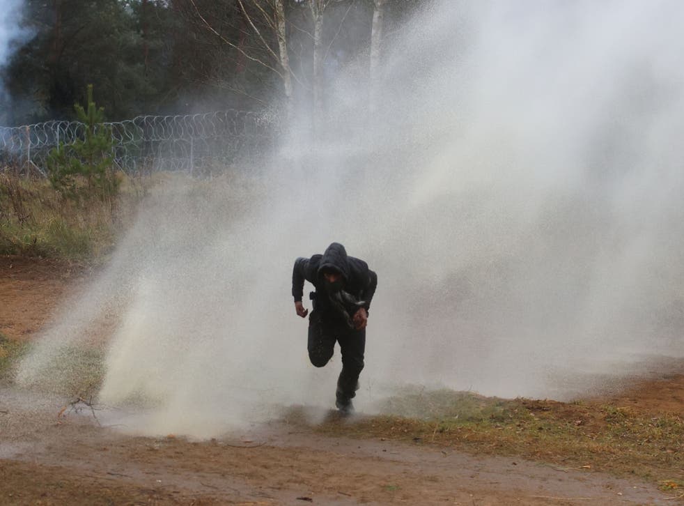 <p>A man runs away from a water cannon used by Polish law enforcement officers</p>