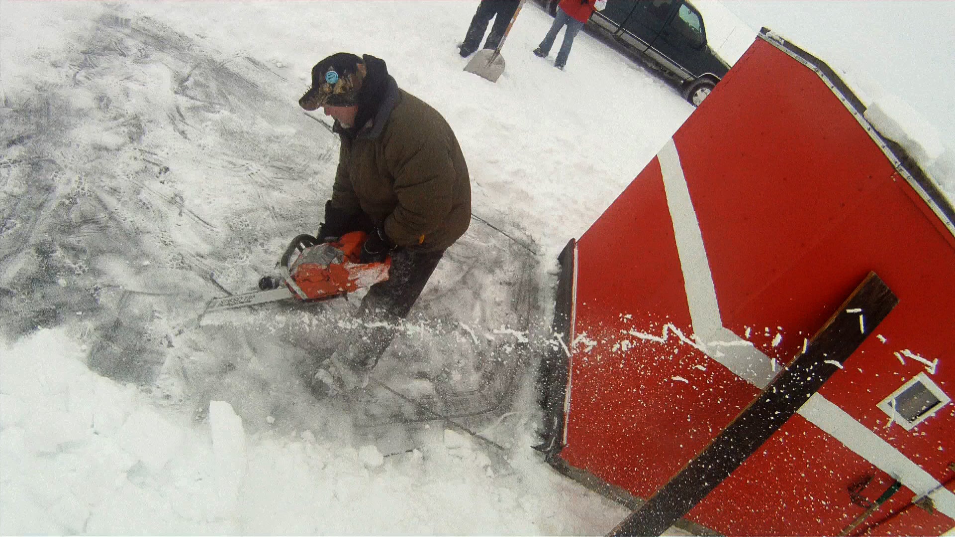 Mark Schumacher uses a large chainsaw to cut through the ice