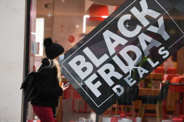 <p>File: A pedestrian wearing a mask because of the novel coronavirus pandemic walks past a shop advertising Black Friday sales on Oxford Street in London on 26 November 2020</p>