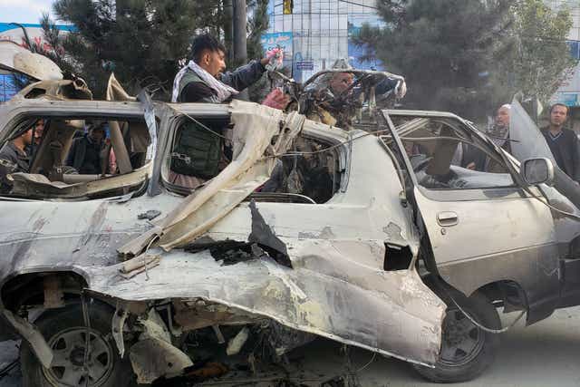 <p>Residents gather next to a damaged minibus after a bomb blast where two people were killed and five wounded in Kabul on November 17, 2021. </p>