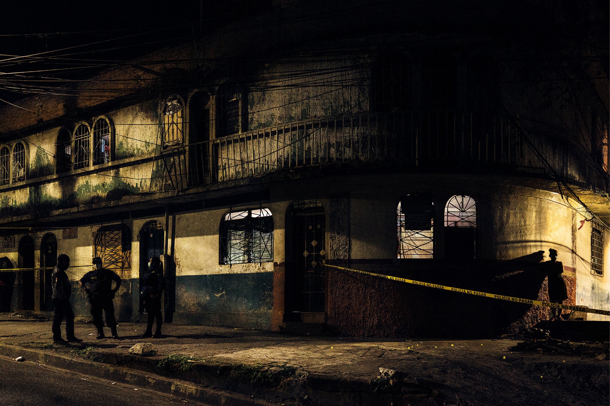 A bystander looks on while police cordon off the area around the body of a murder victim – who was shot eight times – on 38 South Avenue, Terminal de Oriente, Lourdes, San Salvador