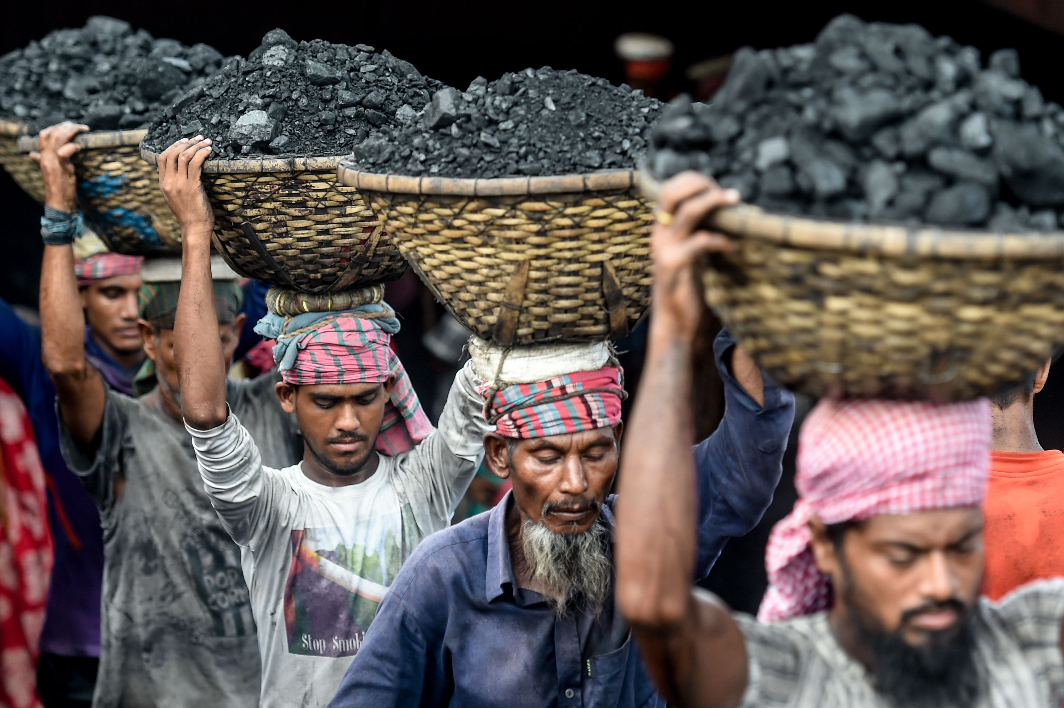 Labourers unload coal from a cargo ship in Dhaka