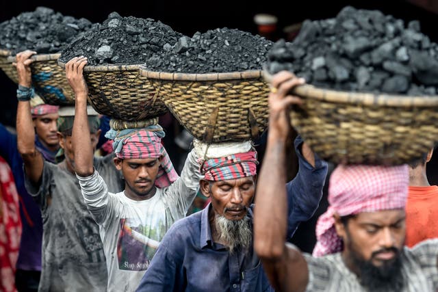 <p>Labourers unload coal from a cargo ship in Dhaka</p>