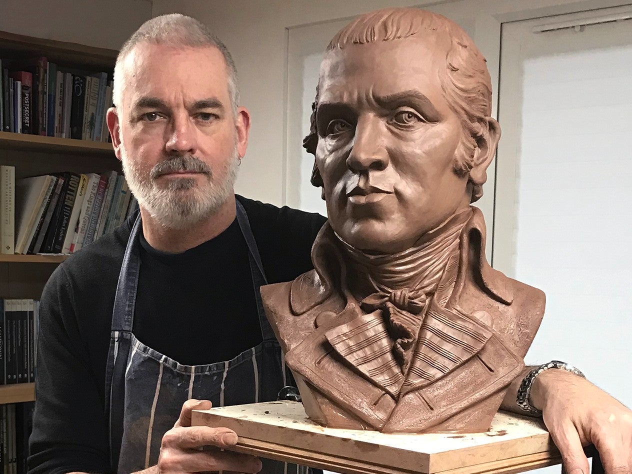 Dave Brown in his studio with the portrait of James Gillray in clay