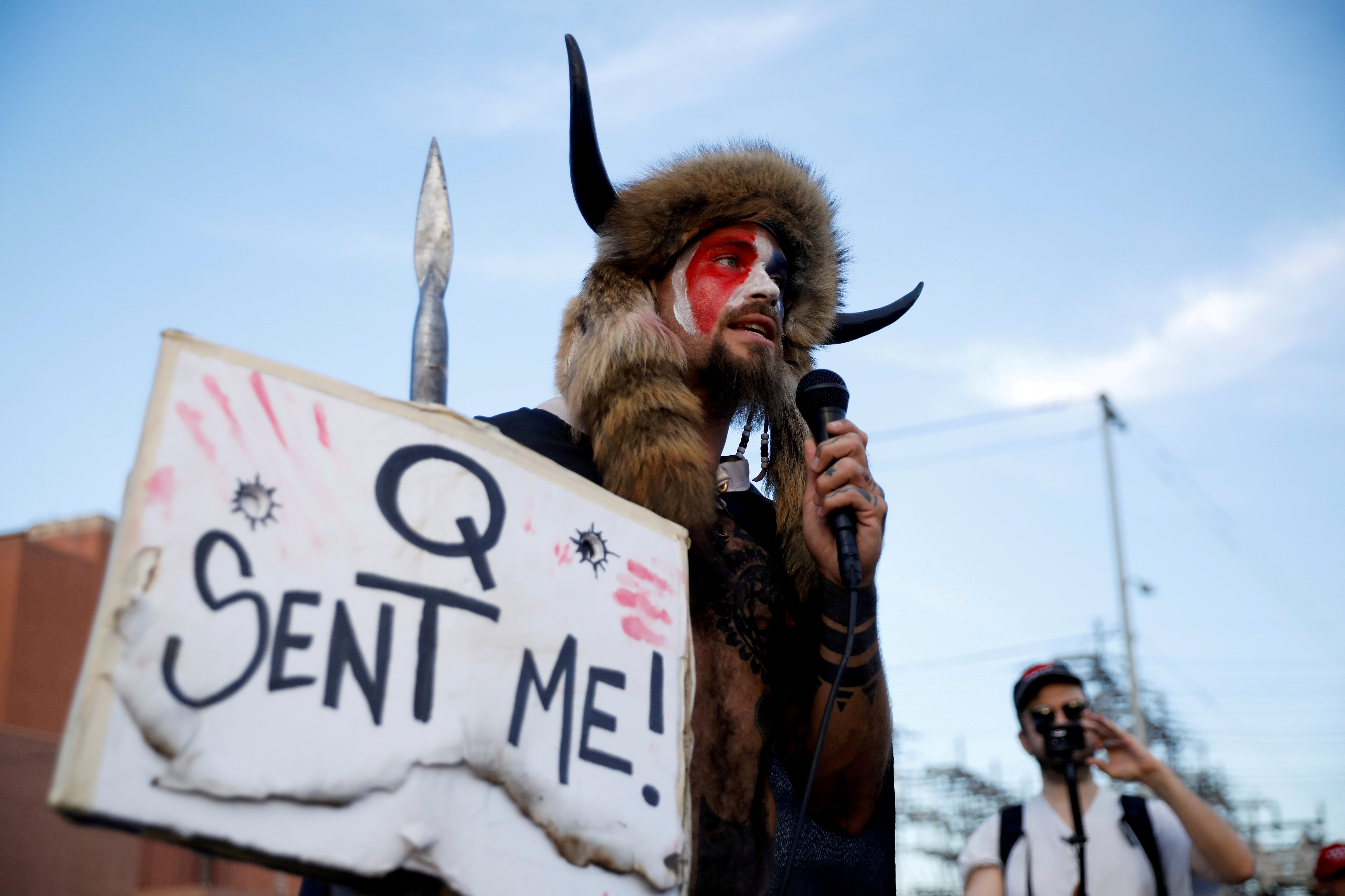 Jacob Chansley, holding a sign referencing QAnon