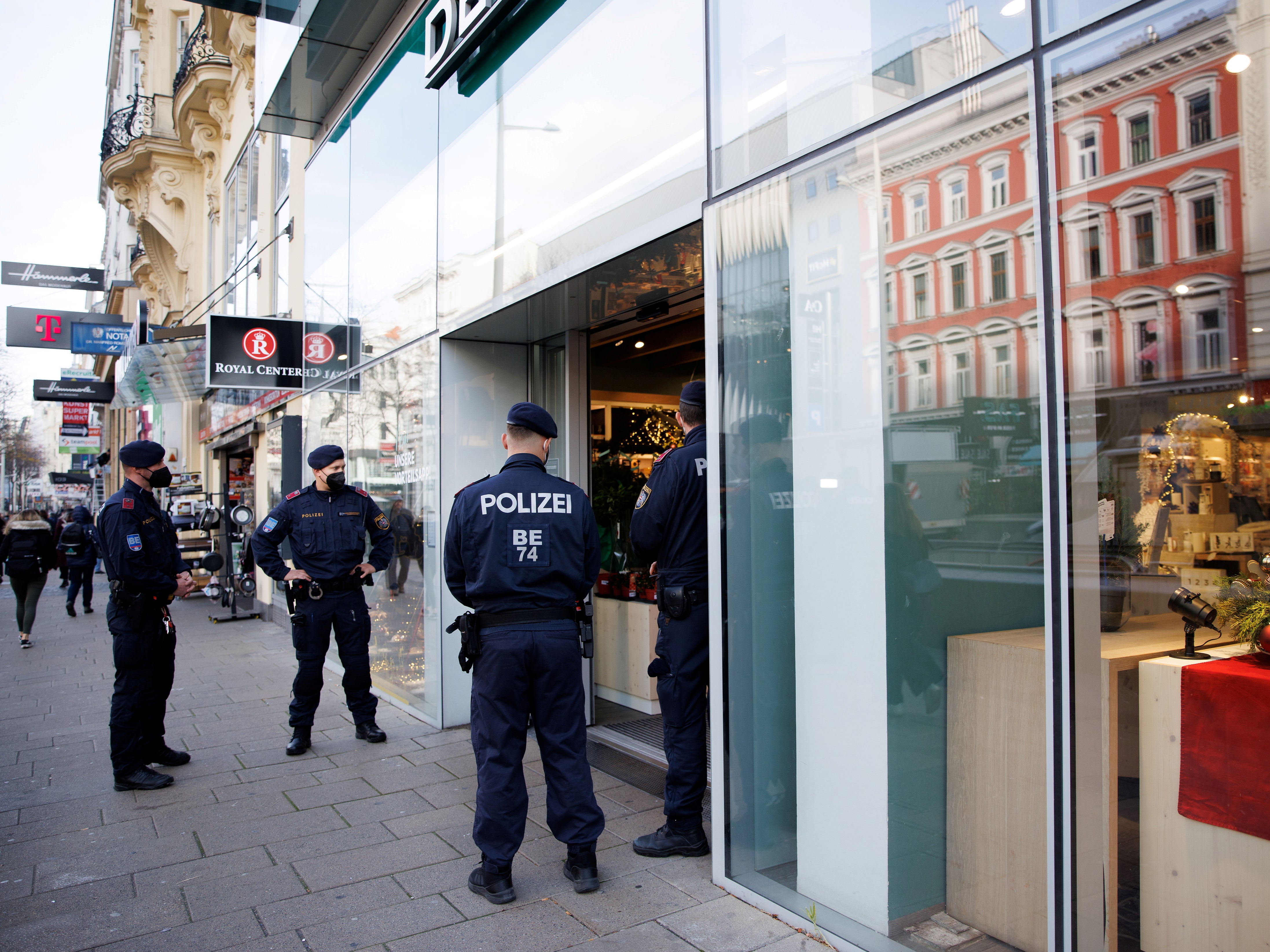 Police officers check the vaccination status of shoppers at the entrance to a store in Vienna