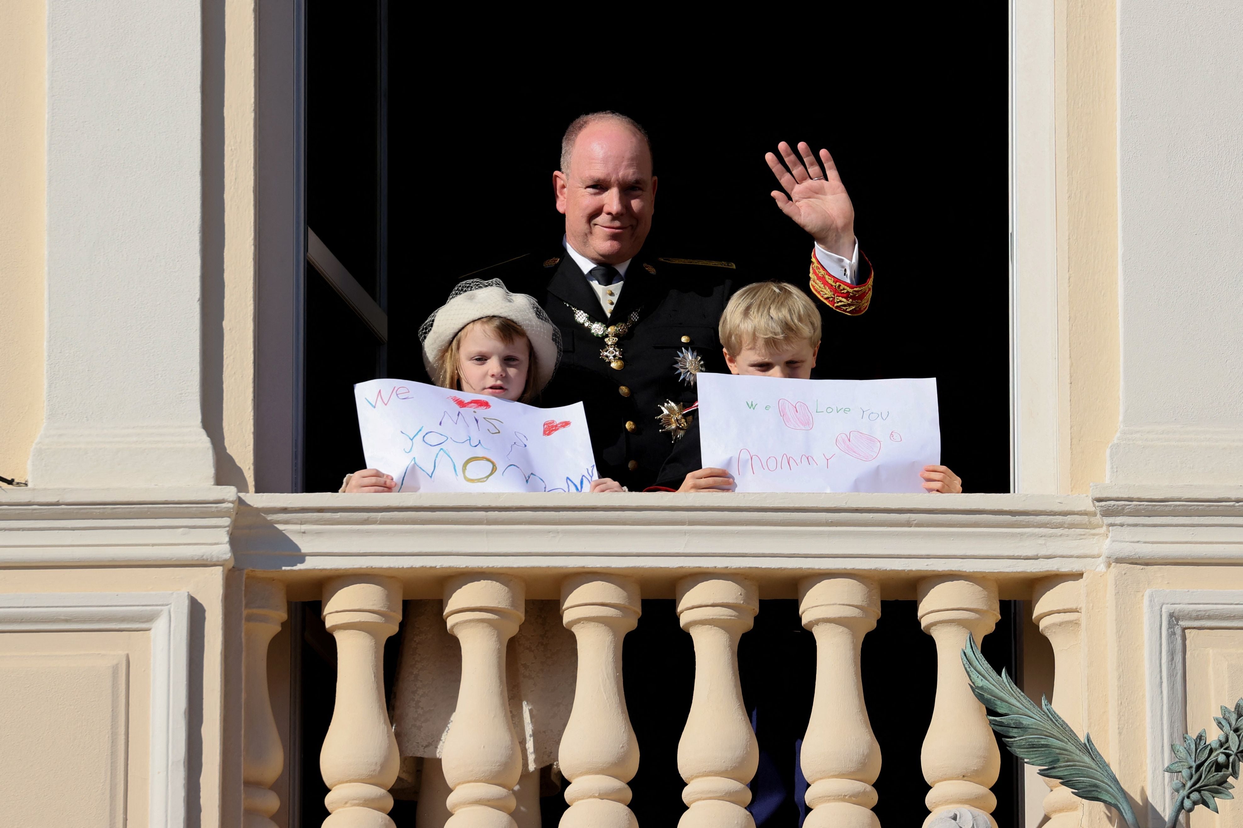 Prince Albert II of Monaco, Princess Gabriella and Prince Jacques stand with a message for Princess Charlene at the balcony of Monaco Palace during the celebrations marking Monacos National Day