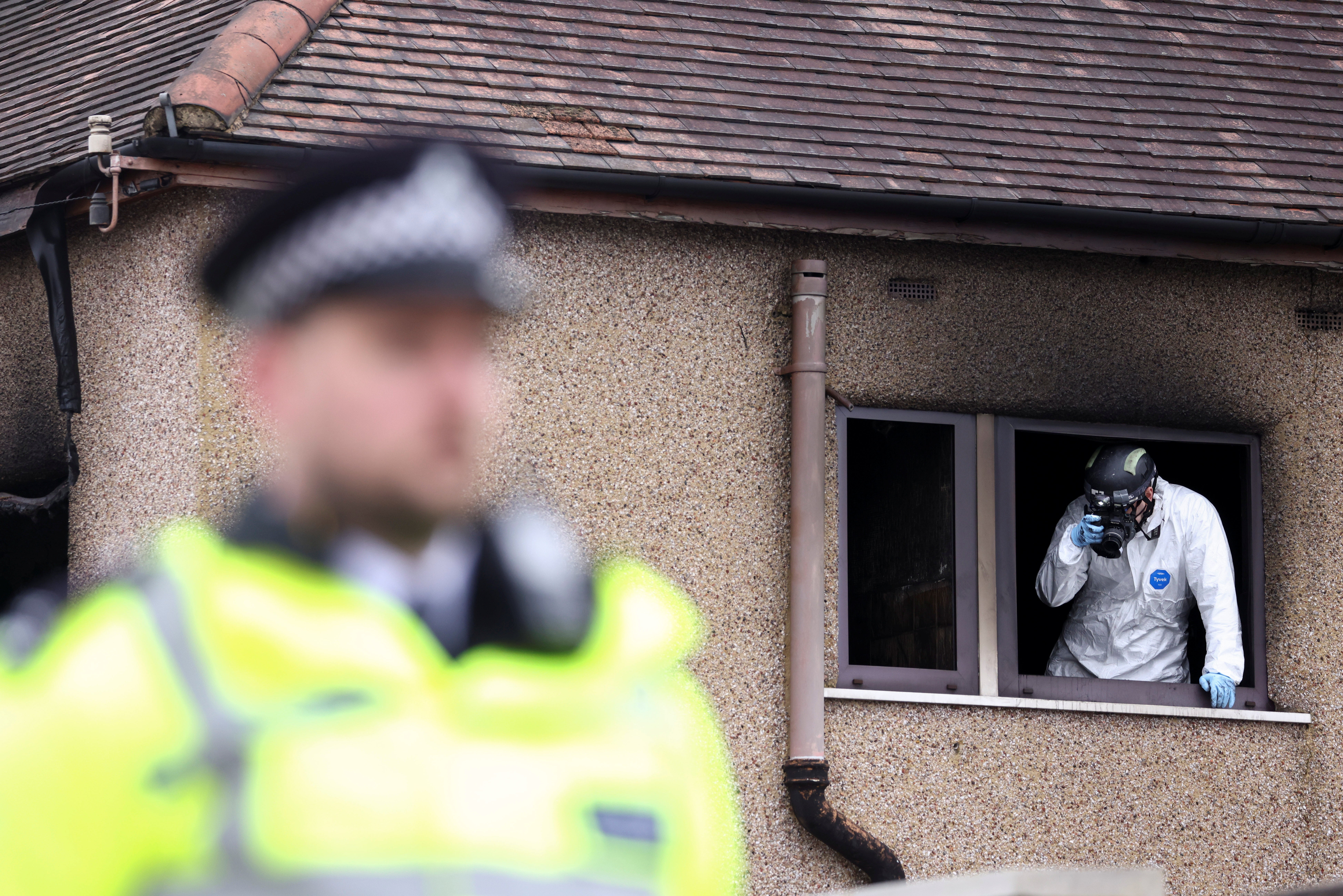 <p>An investigator inspects the scene of a house fire in Bexleyheath</p>