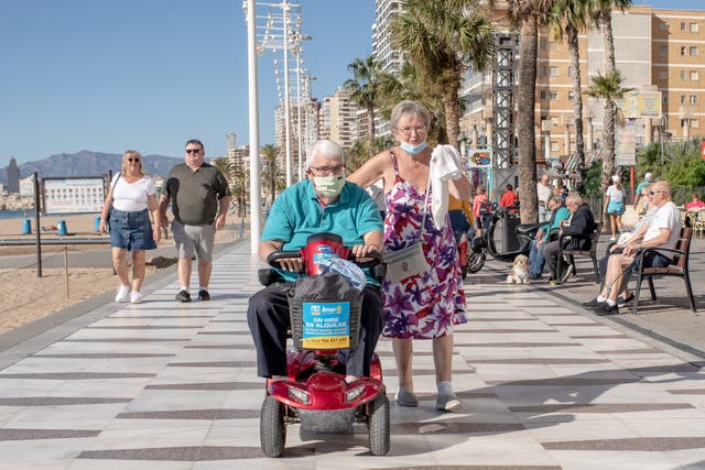 <p> A man drives his mobility scooter along the promenada of Levante beach in Benidorm</p>