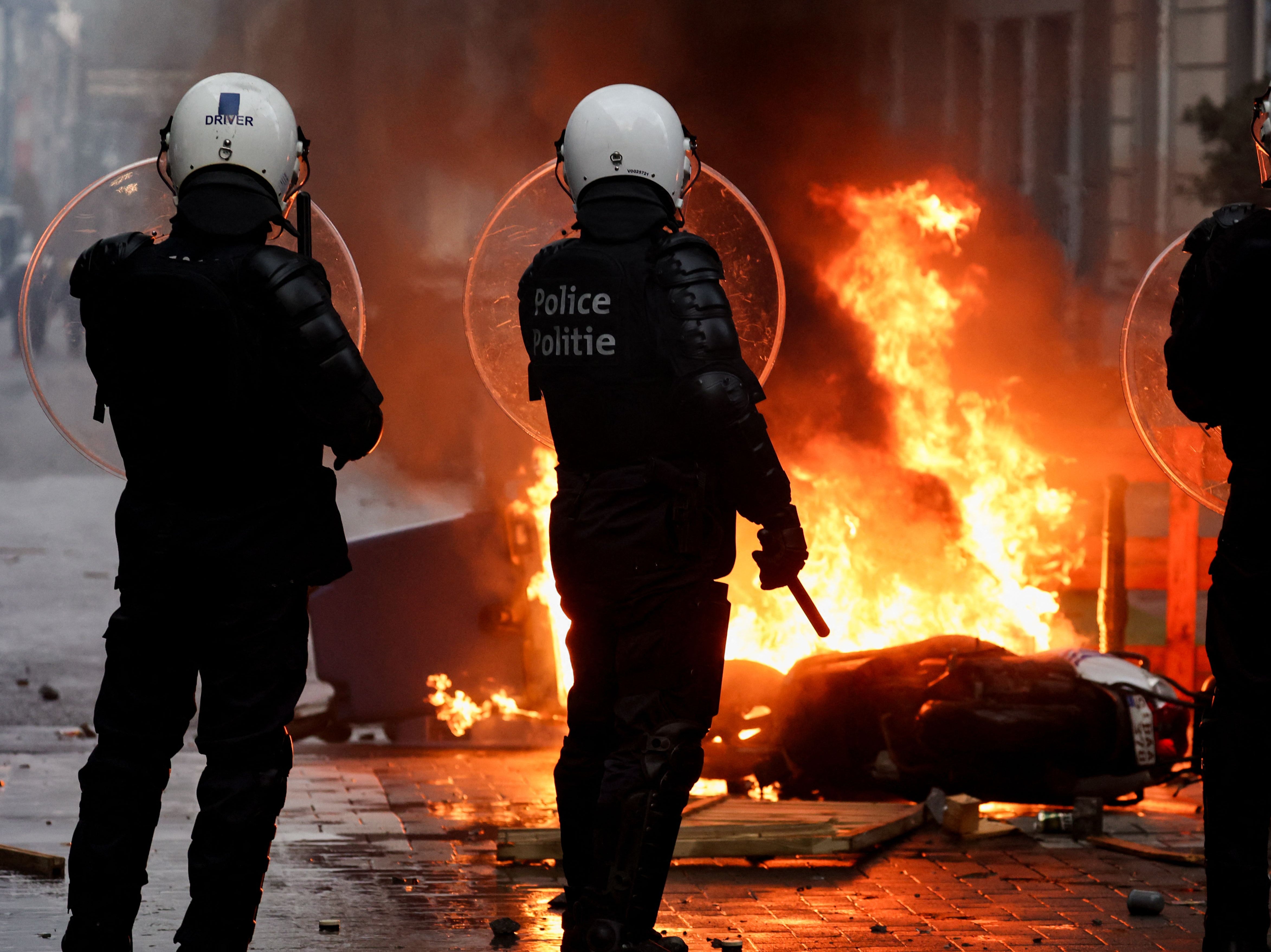 <p>Belgian riot police stand in front of a burning rubbish bin following a protest against Covid restrictions in Brussels</p>