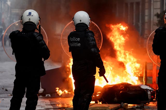 <p>Belgian riot police stand in front of a burning rubbish bin following a protest against Covid restrictions in Brussels</p>