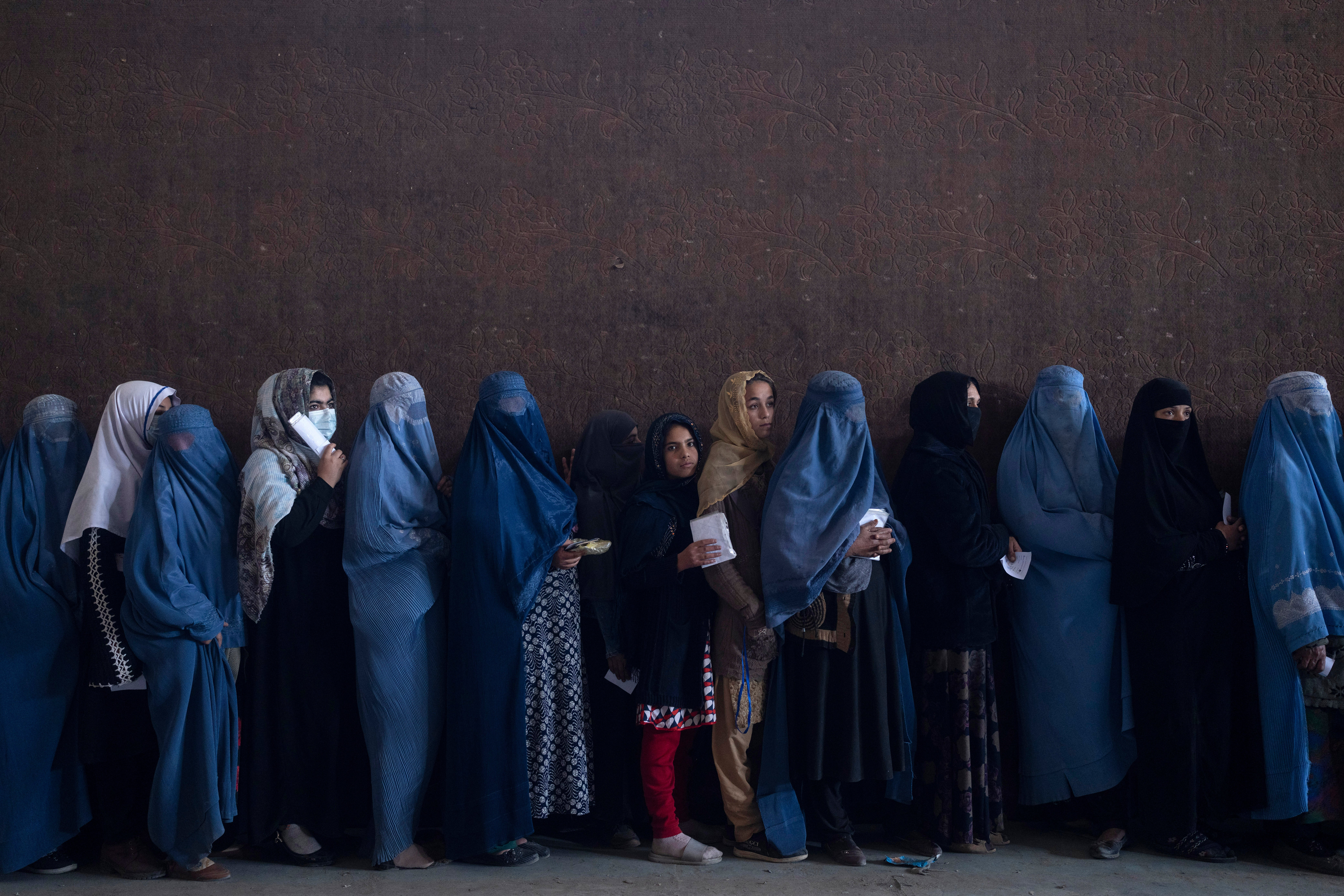 Women line up to receive cash at a money distribution point organised by the World Food Program in Kabul