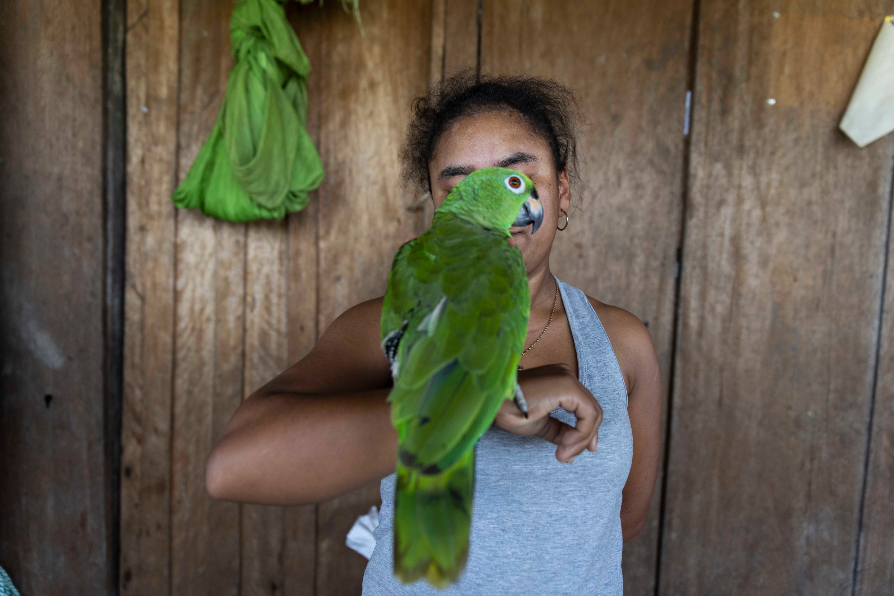 Margie Palacio, secretary of the board of Morichal, a community near Montebello, holds a parrot on her arm