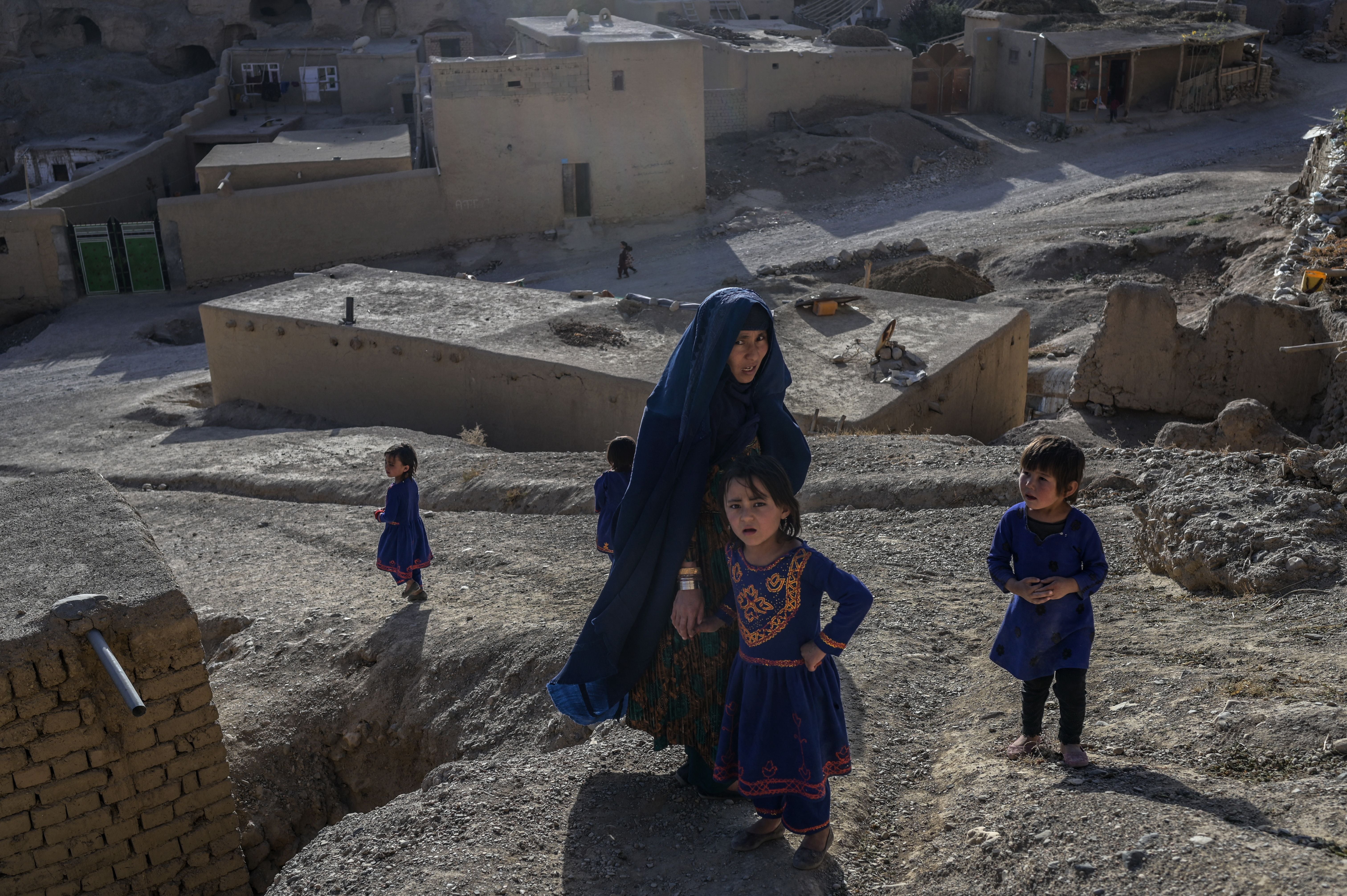 Hazara ethnic woman and children stroll through a village in Bamiyan in central Afghanistan