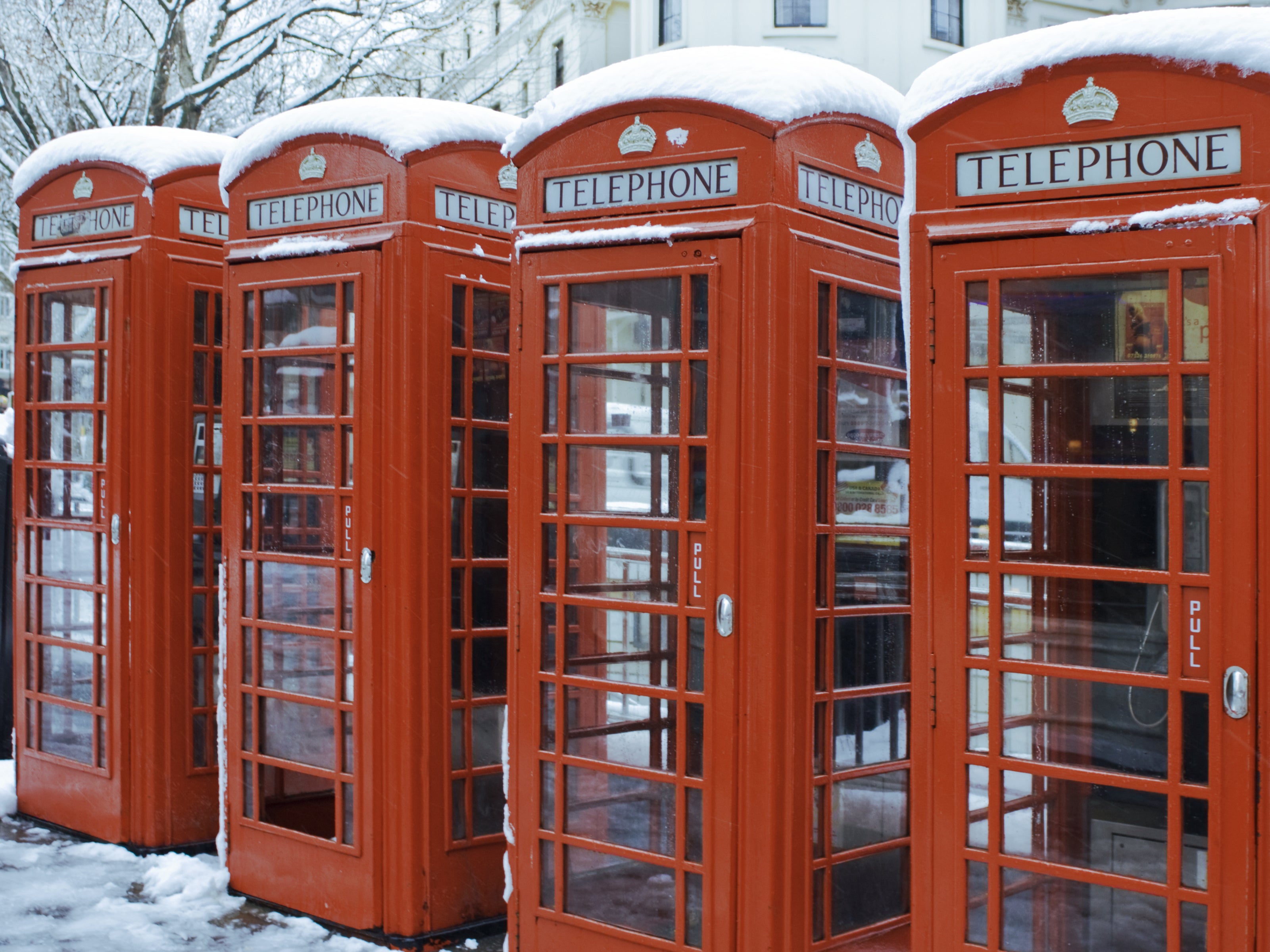 Snow lines red telephone boxes in central London