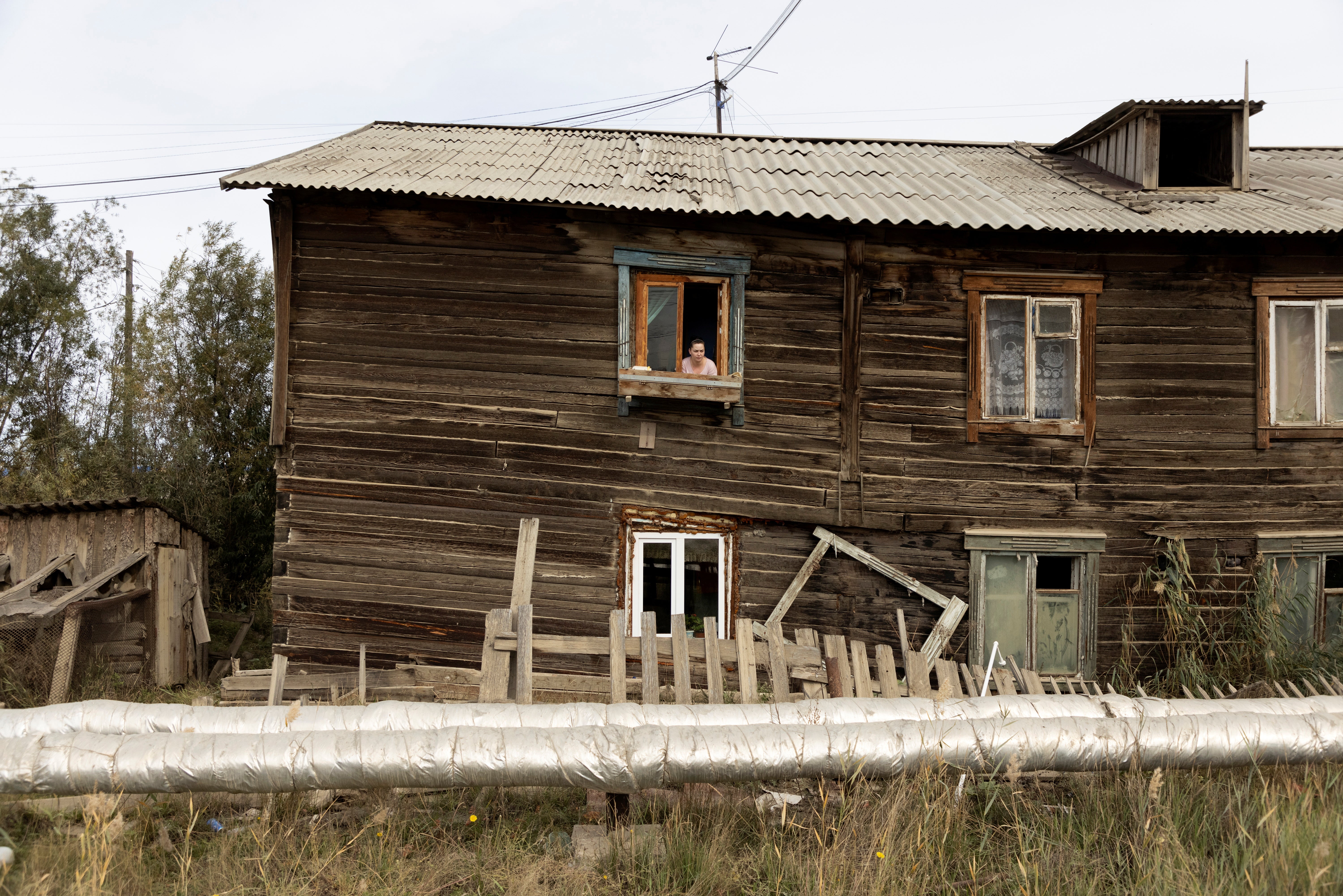 Maria Nedostupenko looks out of the window at her home which was damaged by permafrost under its foundation