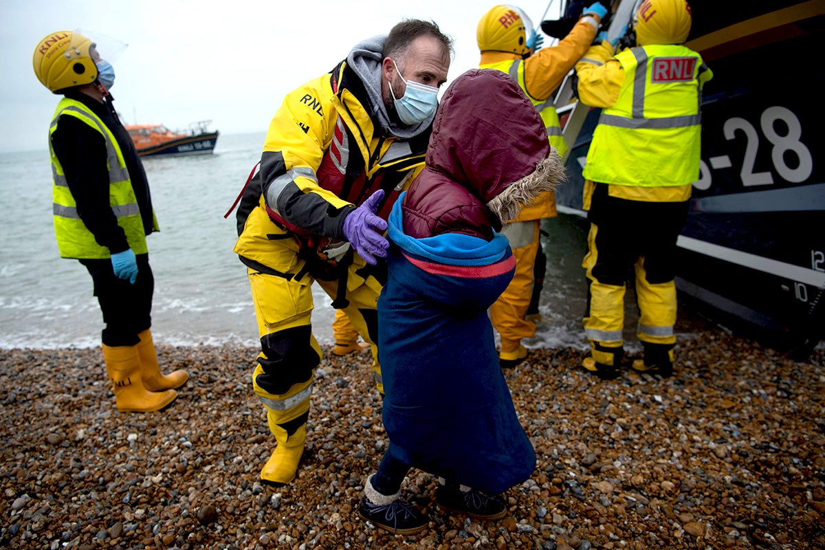 Migrants are helped ashore from a RNLI lifeboat at a beach in Dungeness, on the southeast coast of England, on 24 November