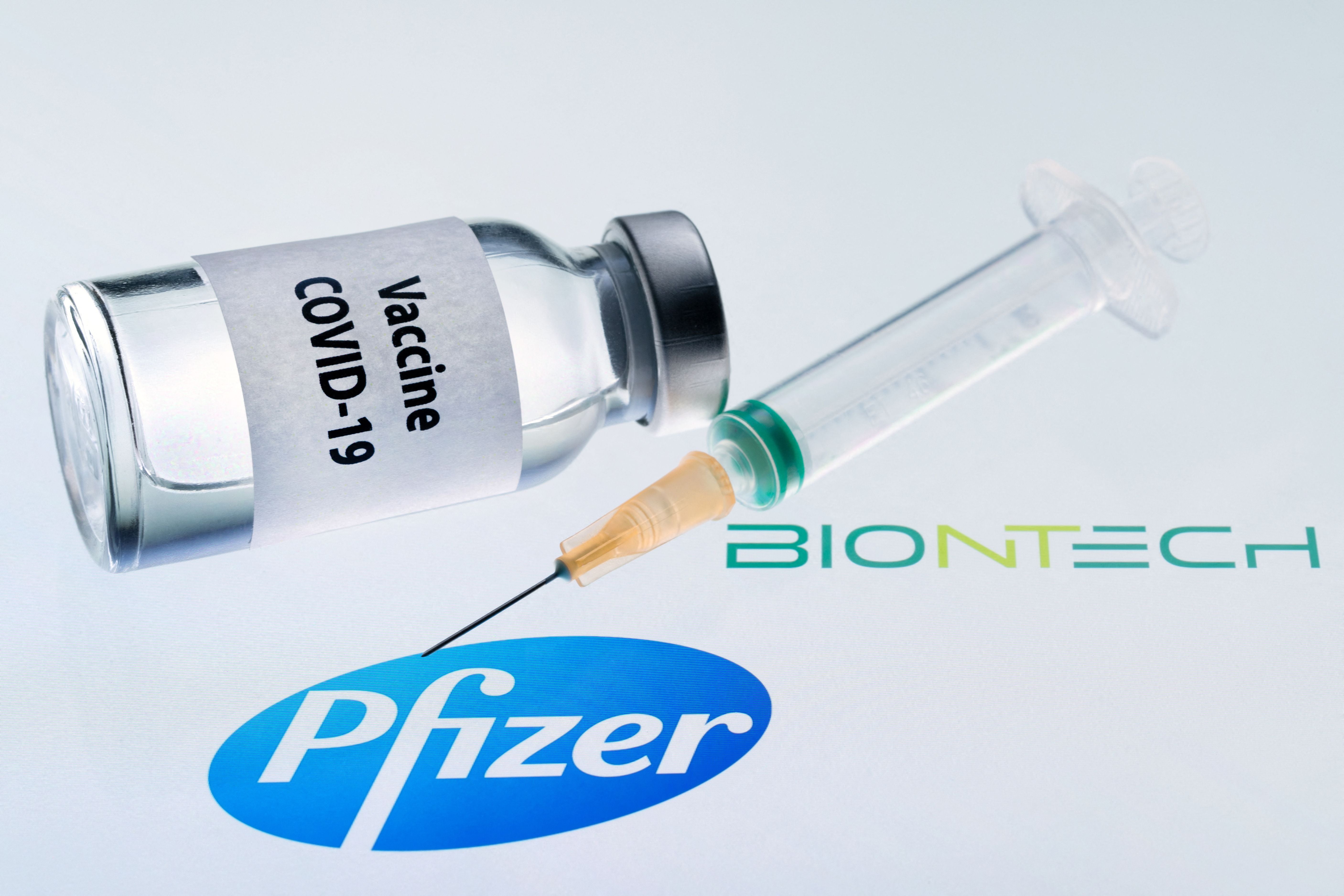 This illustration picture taken on 23 November 2020 shows a bottle reading ‘vaccine Covid-19’ and a syringe next to the Pfizer and BioNTech logo