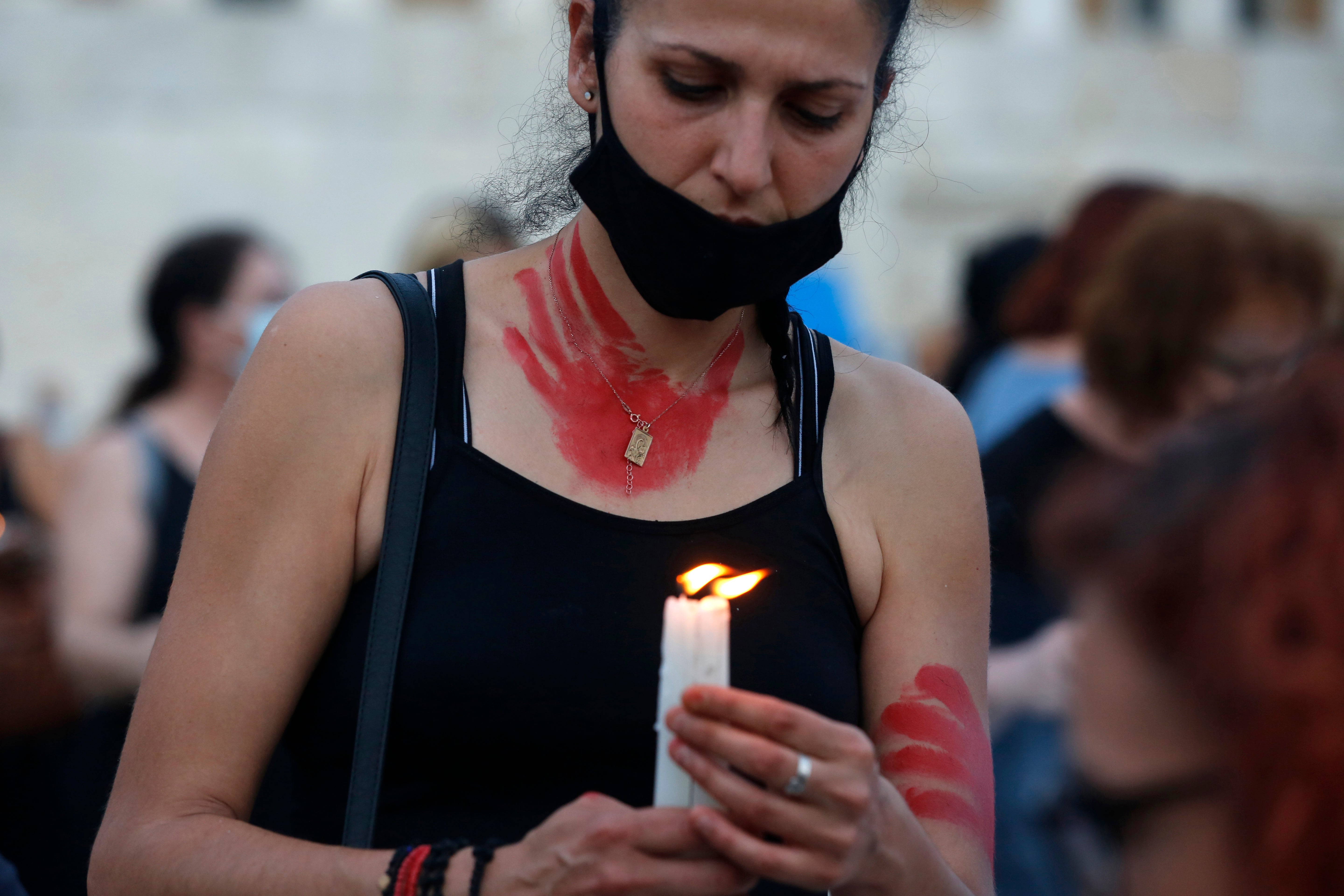 A woman holds candles during a protest against femicide in Athens