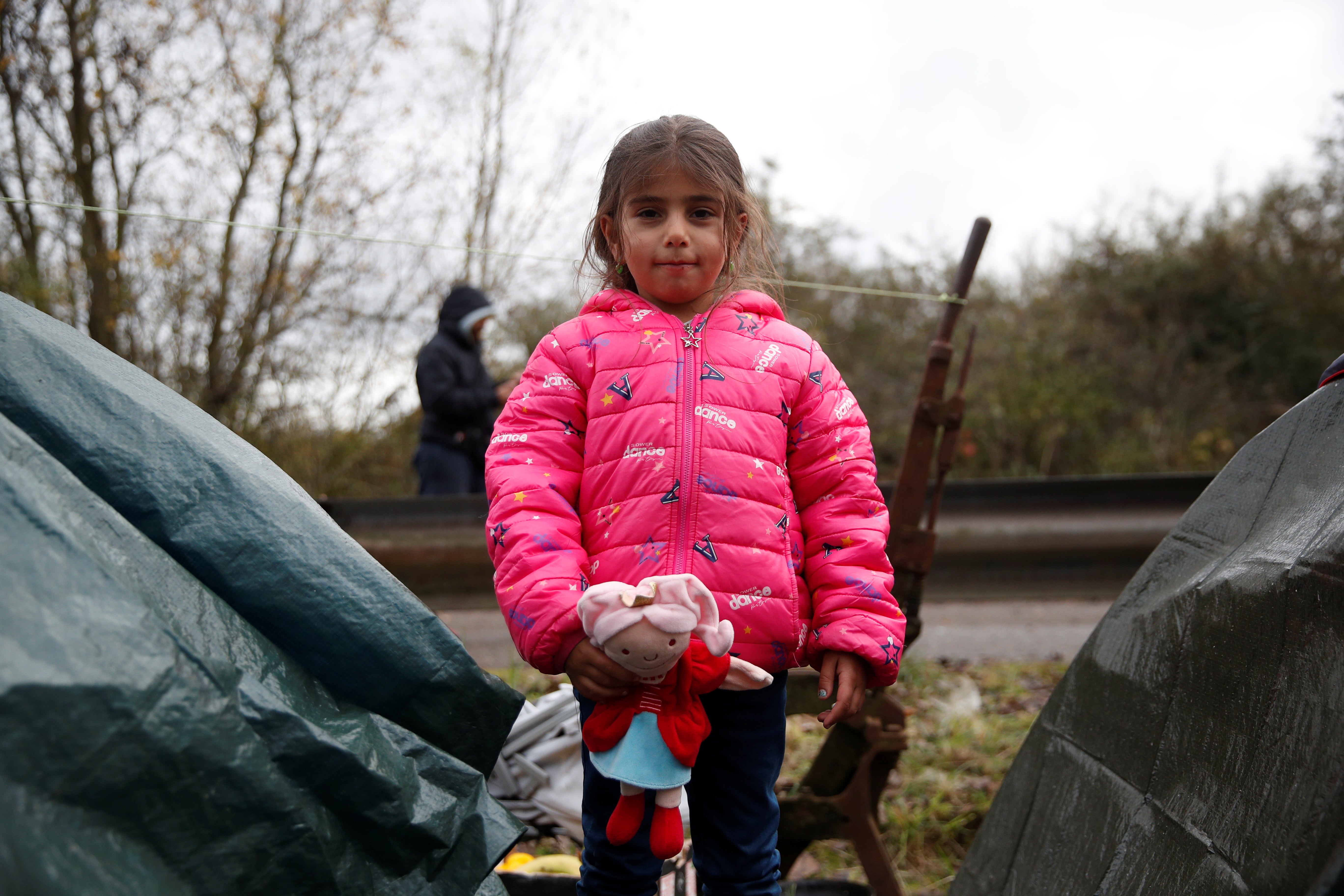 Migrant child Lya from Iraq poses at a makeshift migrant camp in Calais