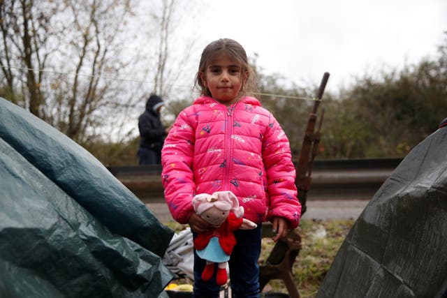 <p>Migrant child Lya from Iraq poses at a makeshift migrant camp in Calais</p>