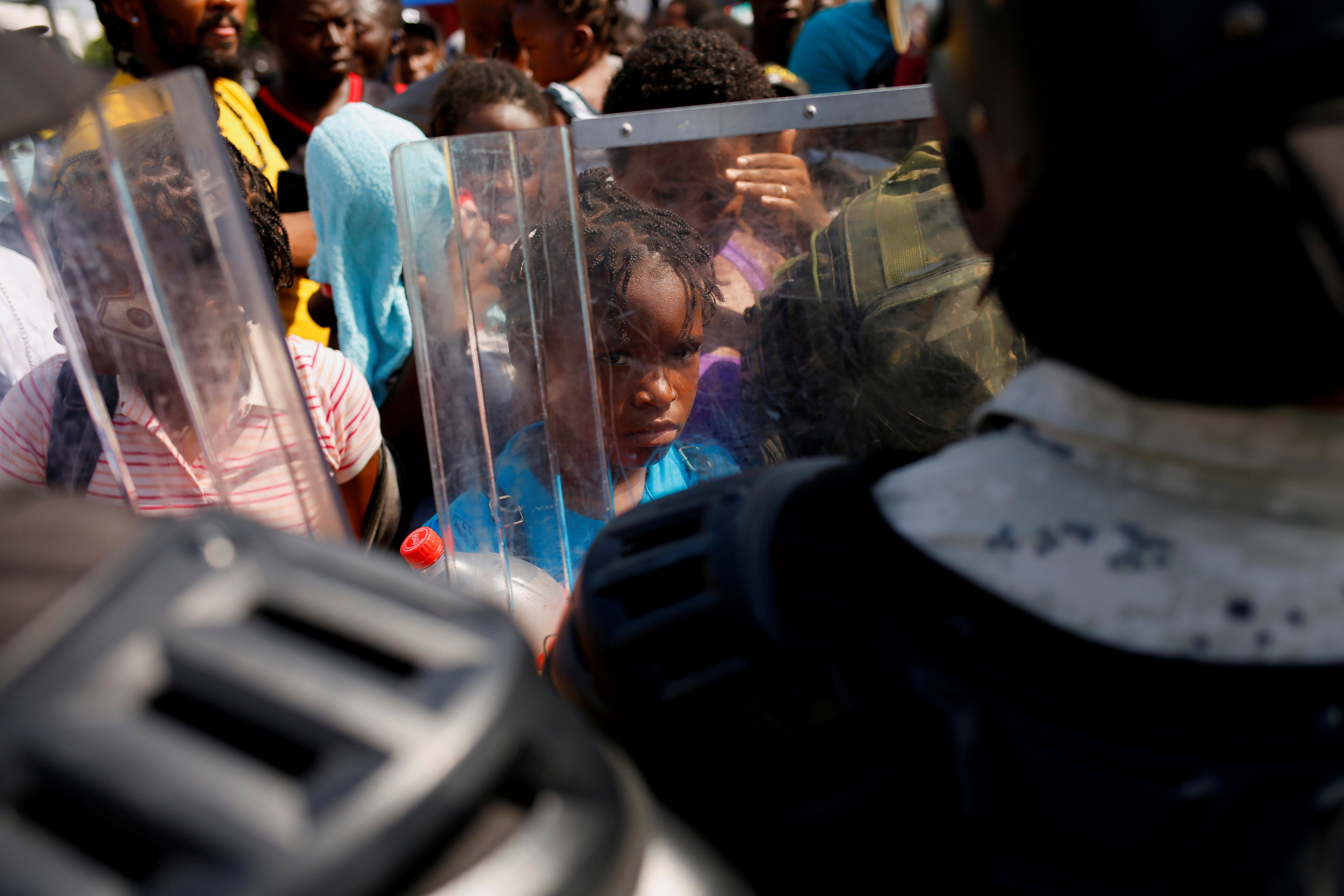 A migrant child is seen through a National Guard member’s shield as he and others queue to get on buses after accepting an offer from the Mexican government to obtain humanitarian visas to transit the Mexican territory, at a stadium in Tapachula, Mexico 25 November 2021