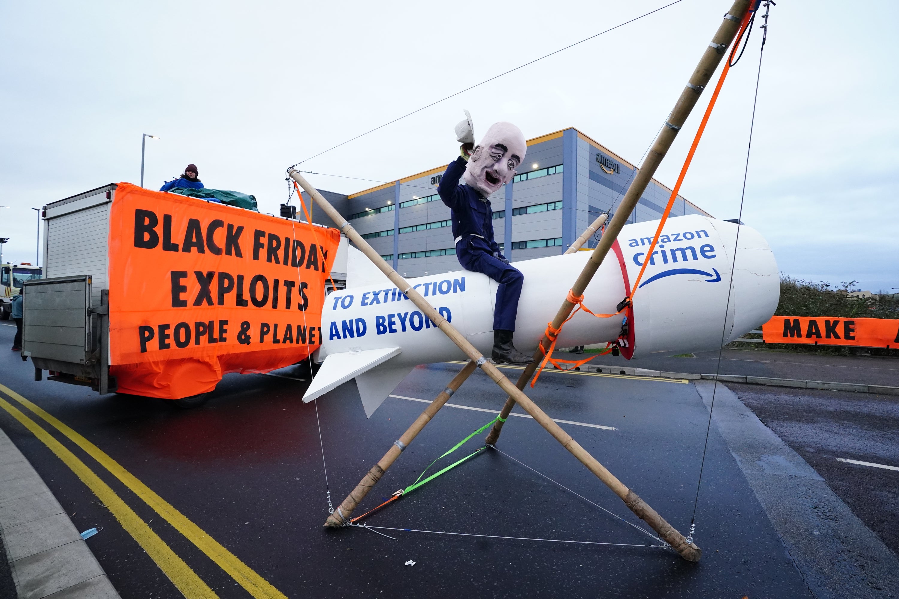 An activist from Extinction Rebellion, wearing a giant Jeff Bezos head, blocks the entrance to the Amazon centre in Tilbury, Essex (Ian West/PA)