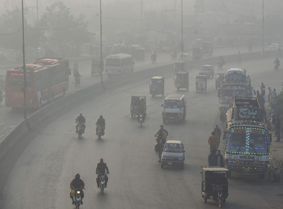 <p>In this picture taken on 24 November 2021, commuters make their way along a road amid smoggy conditions in Lahore</p>