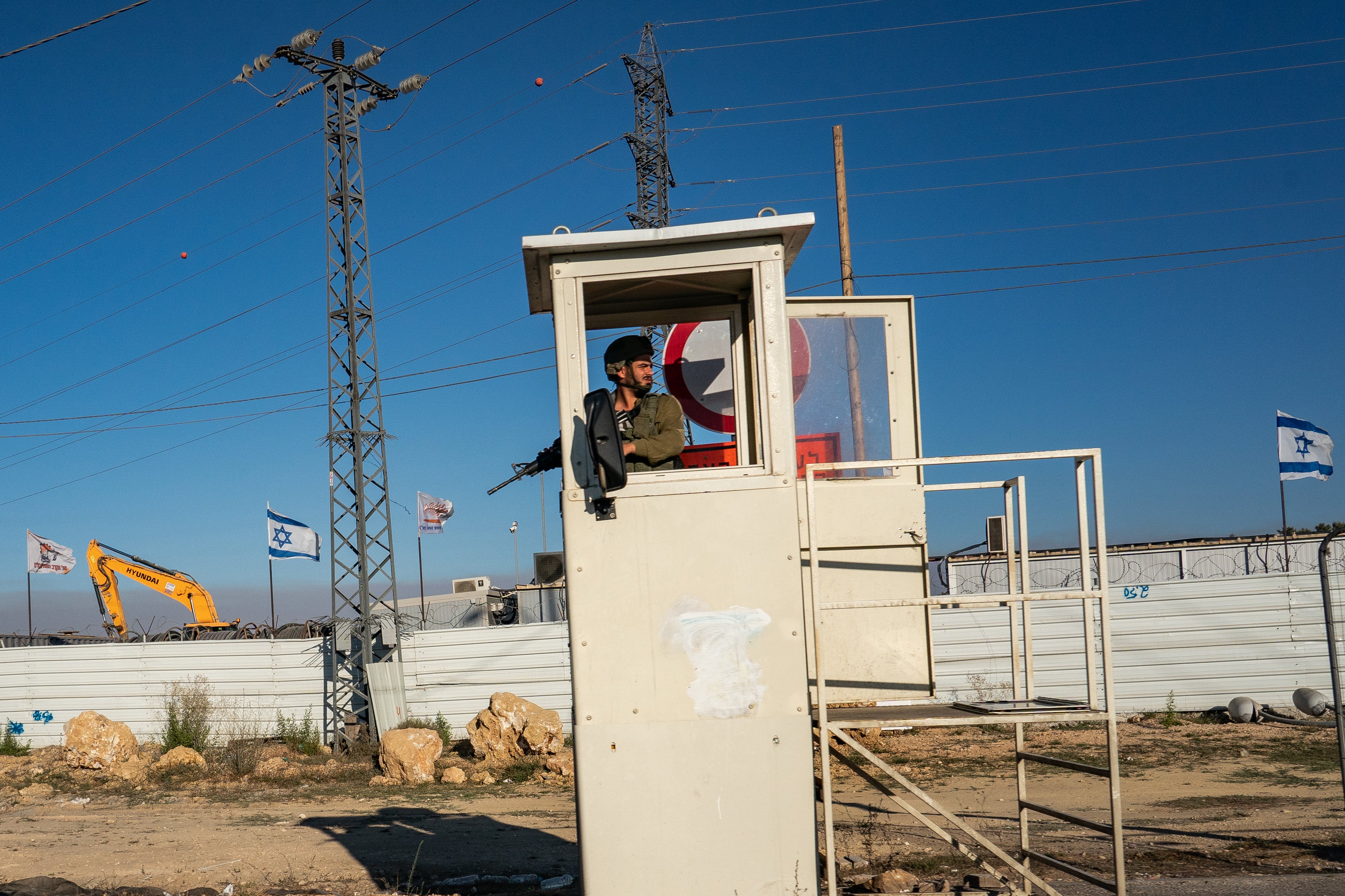 An Israeli soldier is positioned at a bus stop on Route 60 serving an Israeli settlement near Bethlehem