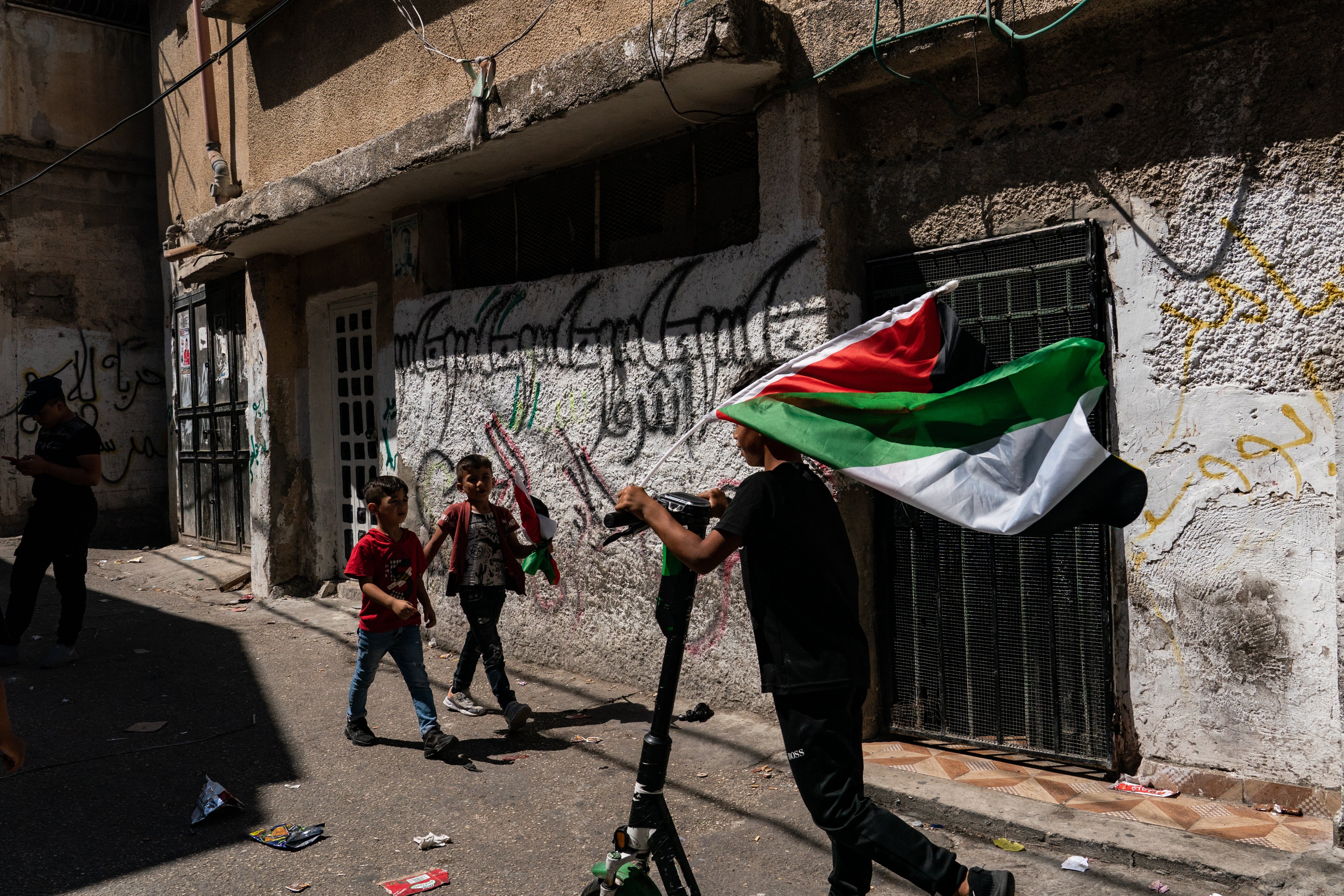 A boy holds a Palestinian flag ahead of the funeral for a teenager fatally shot by Israeli forces during a night raid near Nablus in the West Bank