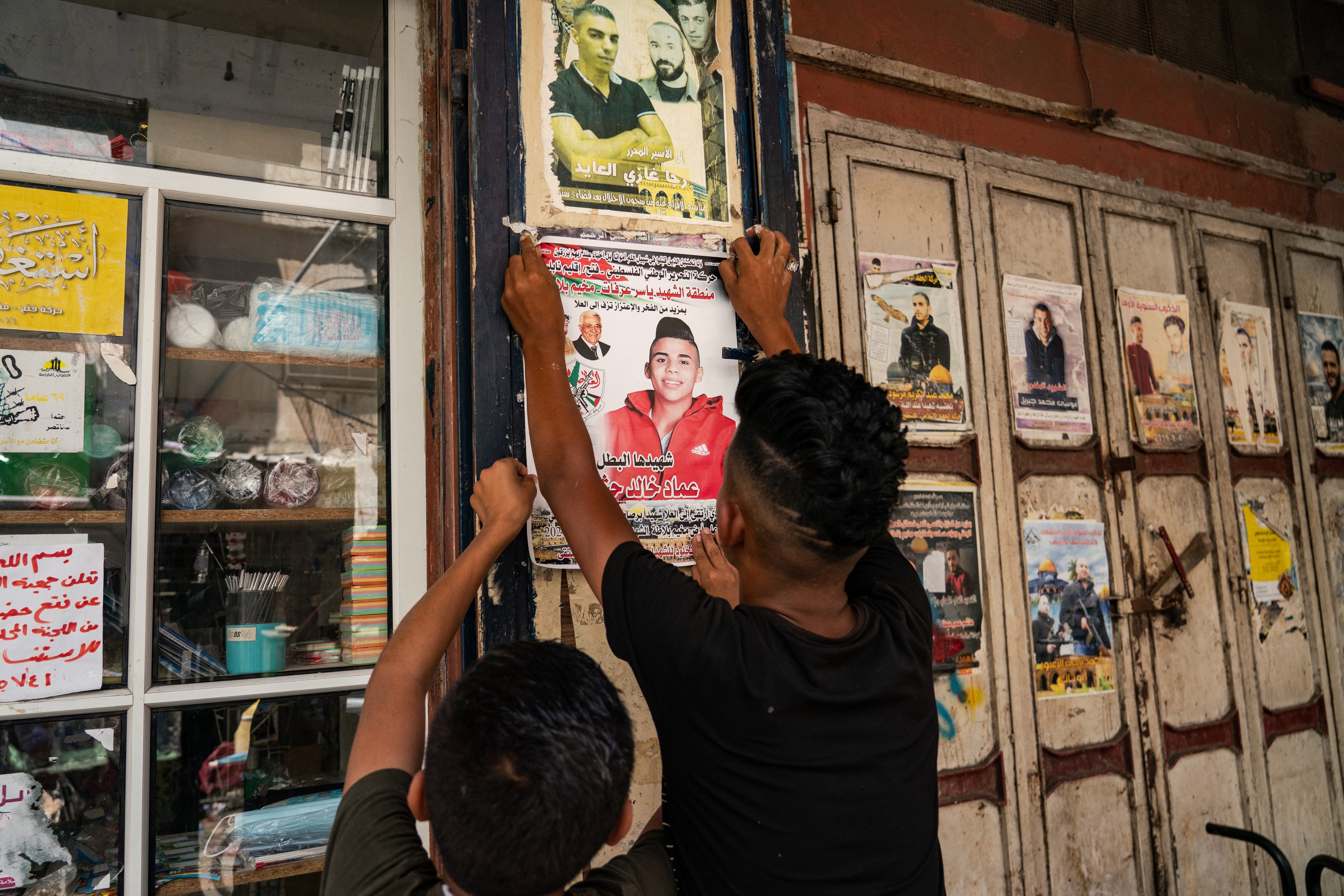 Palestinian children in the West Bank city of Nablus hang a poster of a teenager shot dead during an Israeli raid