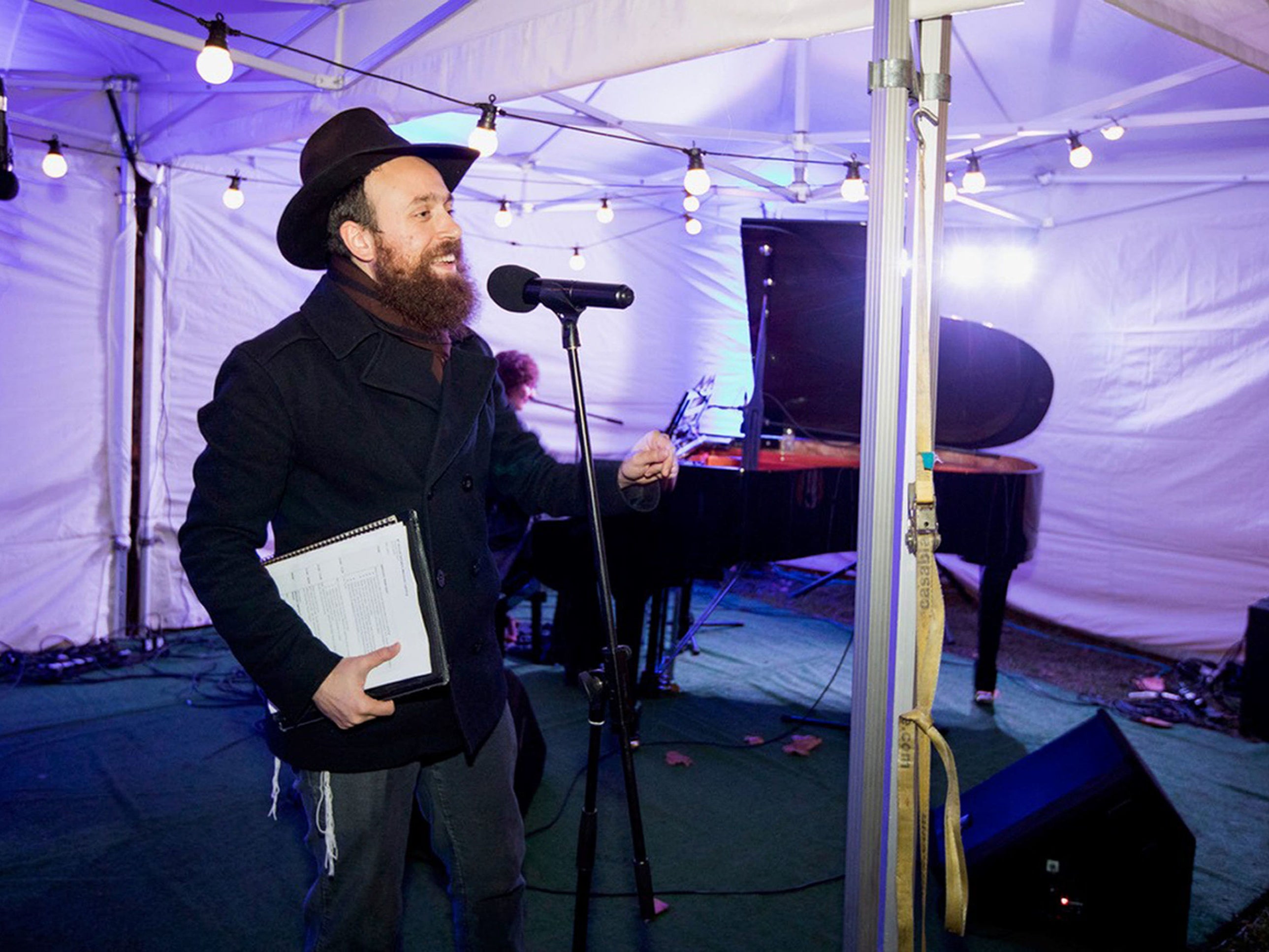 <p> Rabbi Mendy Korer, co-CEO at Chabad Islington, talking on stage at a previous Islington menorah lighting</p>