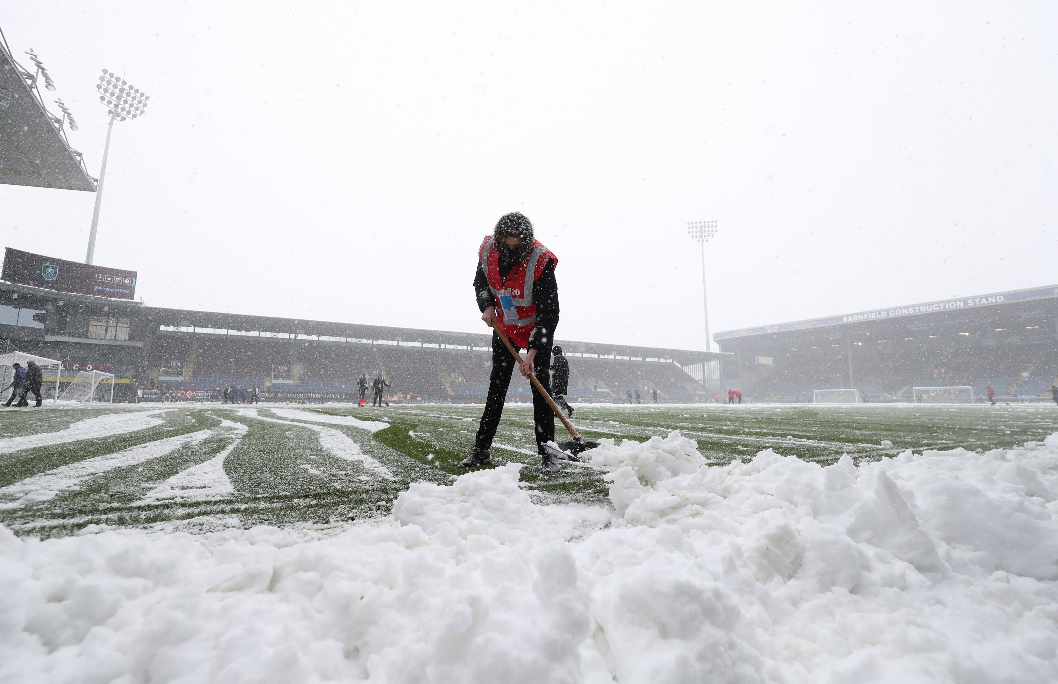 Snow is cleared from the pitch before the Premier League match at Turf Moor, Burnley